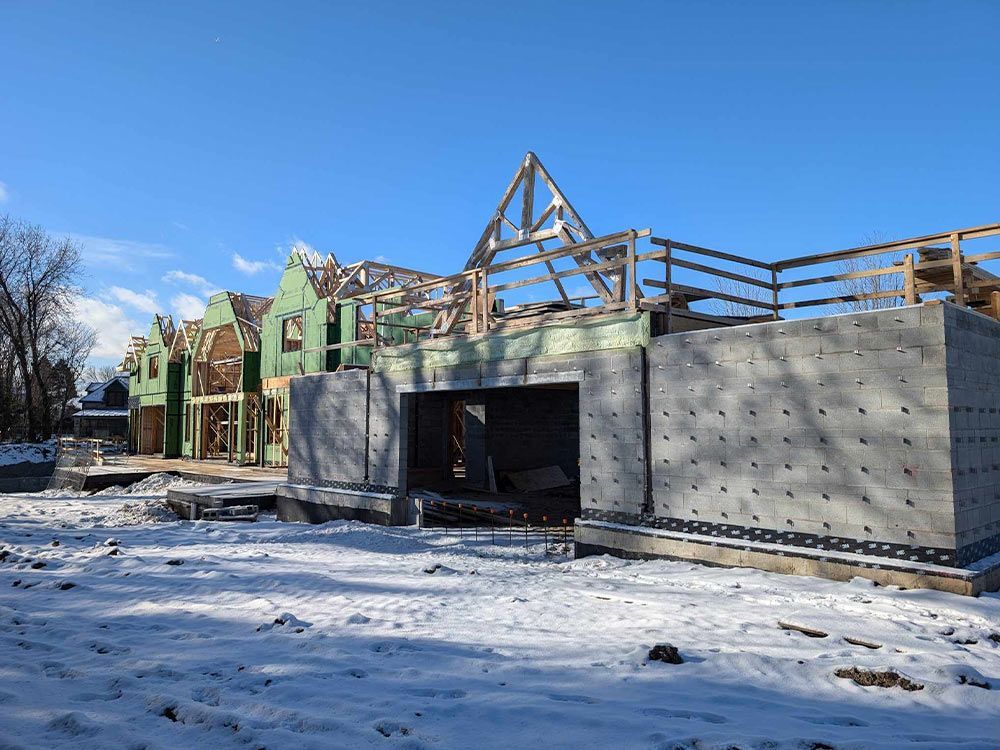Chantier de construction en hiver, sous la neige. Nouvelles charpentes et murs en béton sous un ciel bleu dégagé.