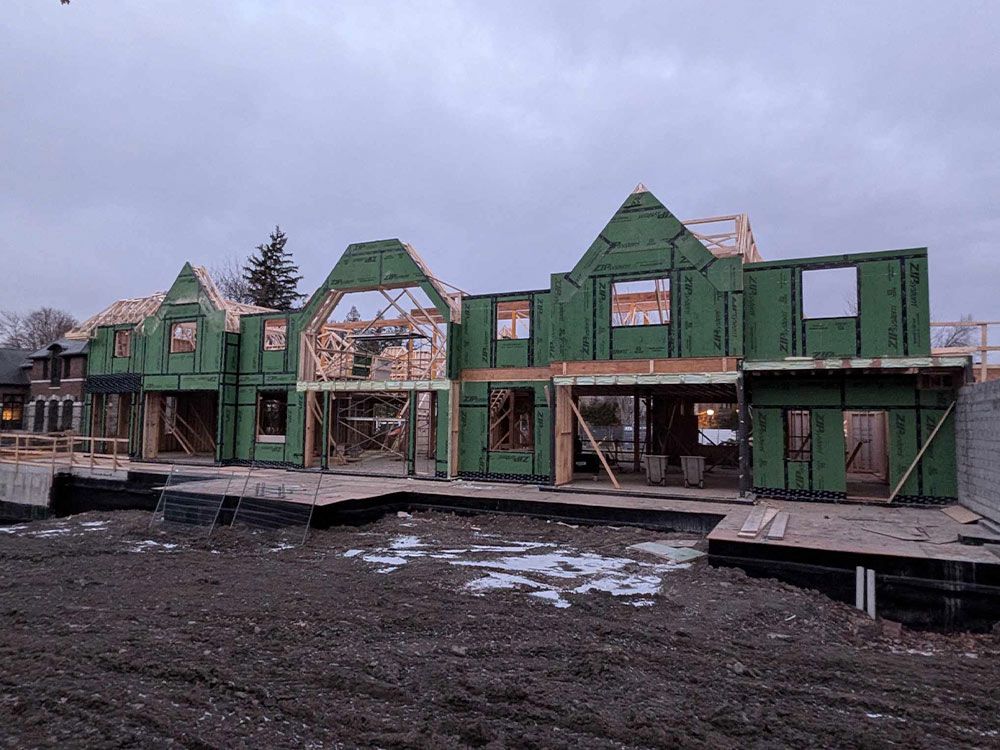 Chantier de construction d'un immeuble résidentiel collectif ; structure en bois et bardage vert. Ciel nuageux.