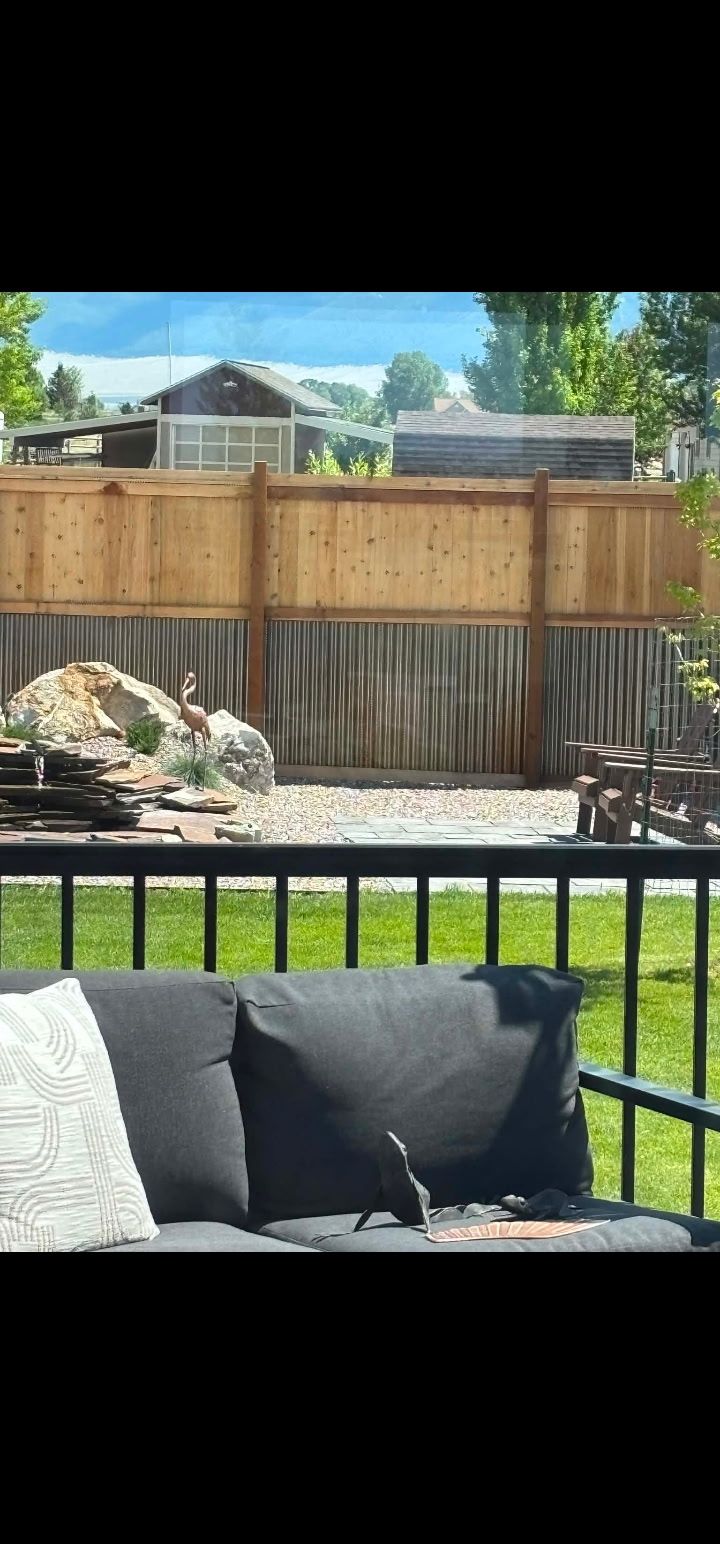 Outdoor patio with black chair cushions, wood fence, and a sunny backyard view.