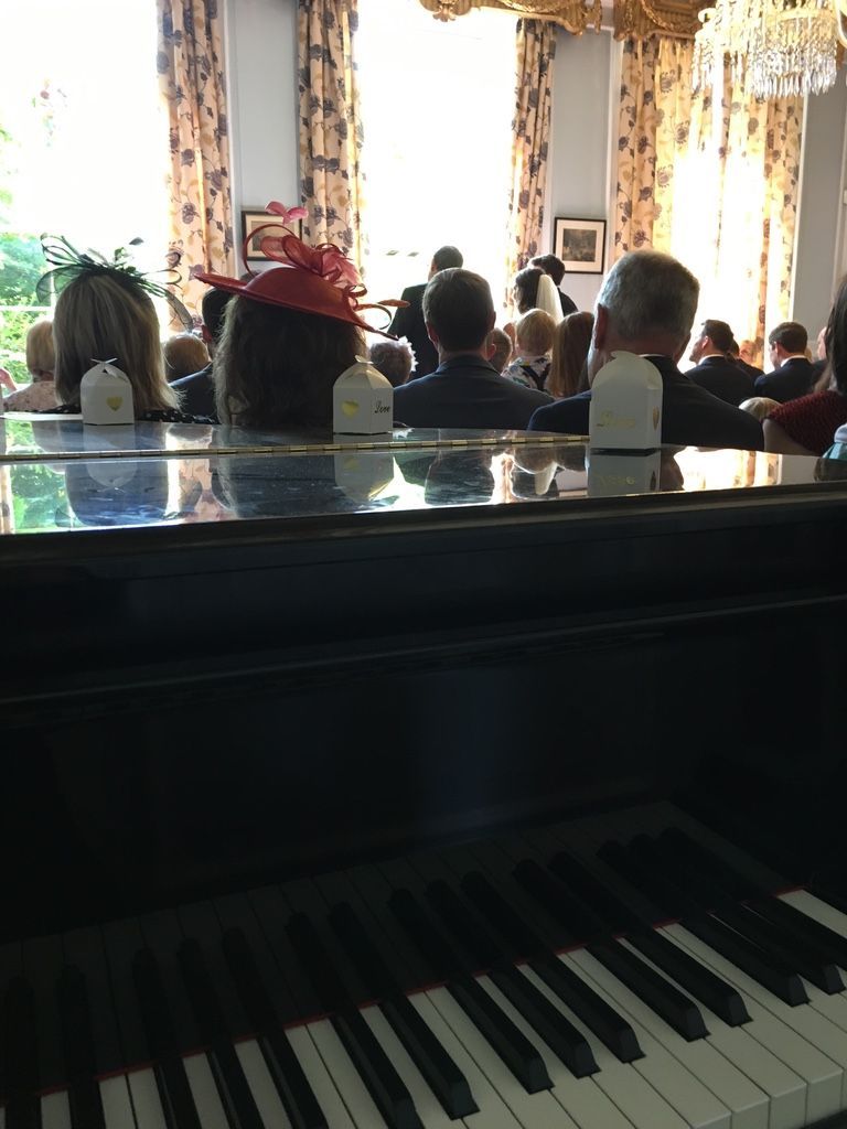 A grand piano with a closed lid in the corner of a wedding ceremony