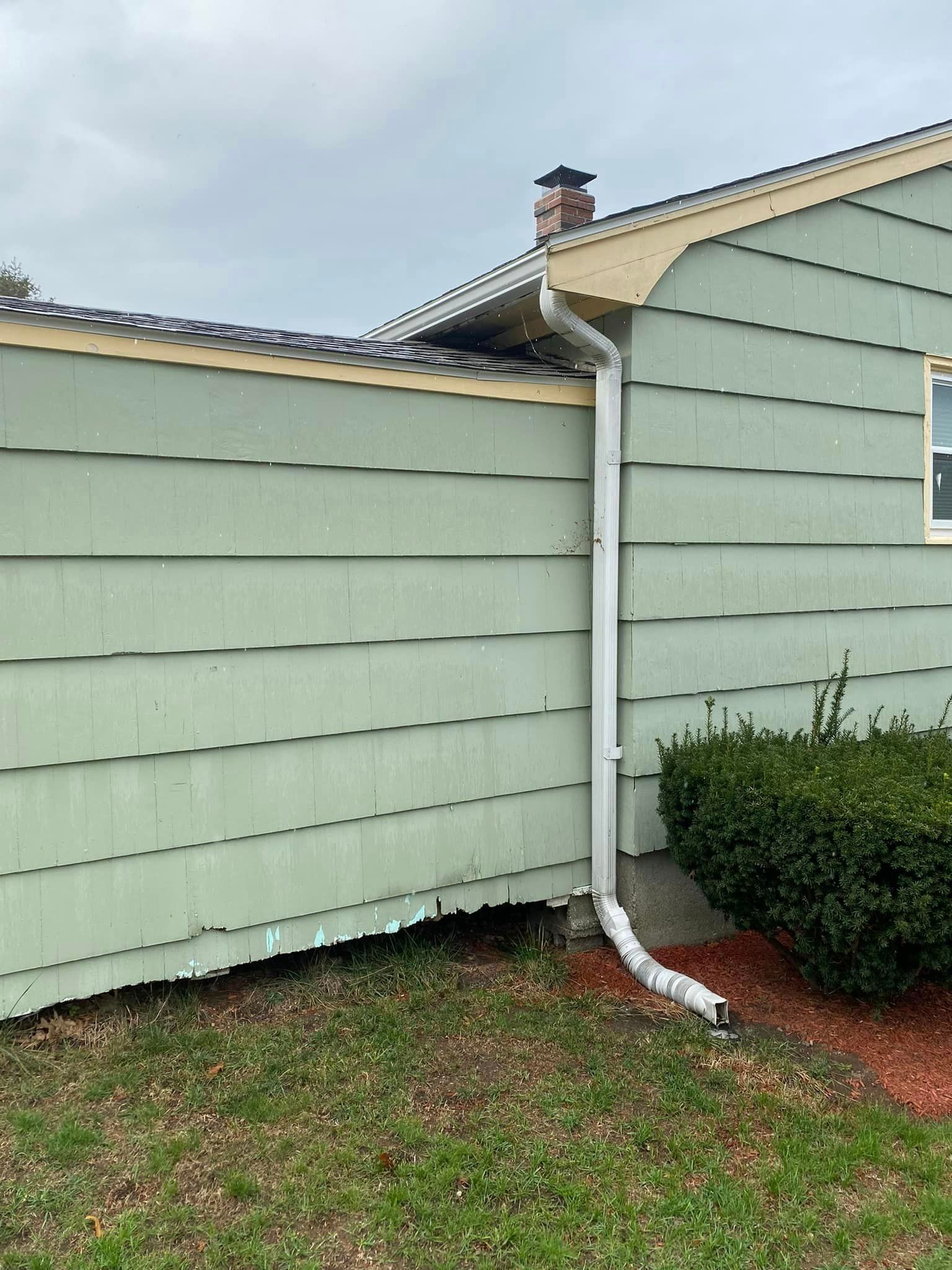 A house with a white gutter on the side of it.