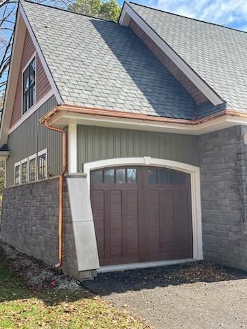 A house with a brown garage door and a copper gutter.