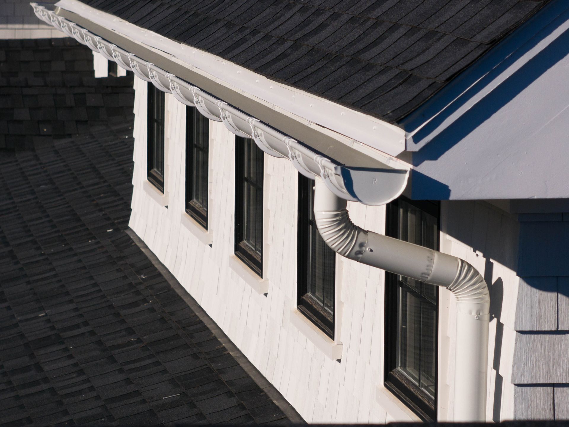 A white house with a black roof and a white gutter