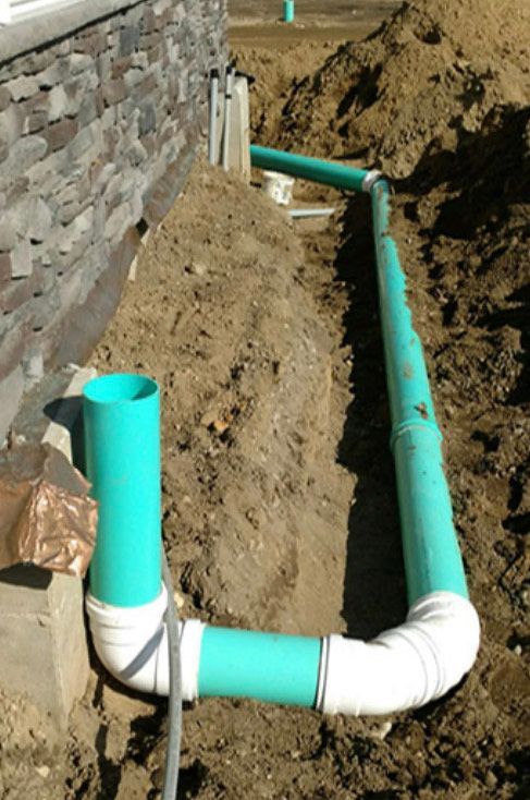 A bunch of green pipes are laying in the dirt