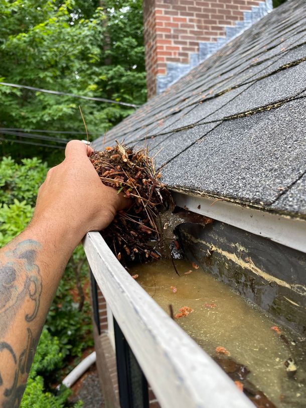 A person is cleaning a gutter on a roof.