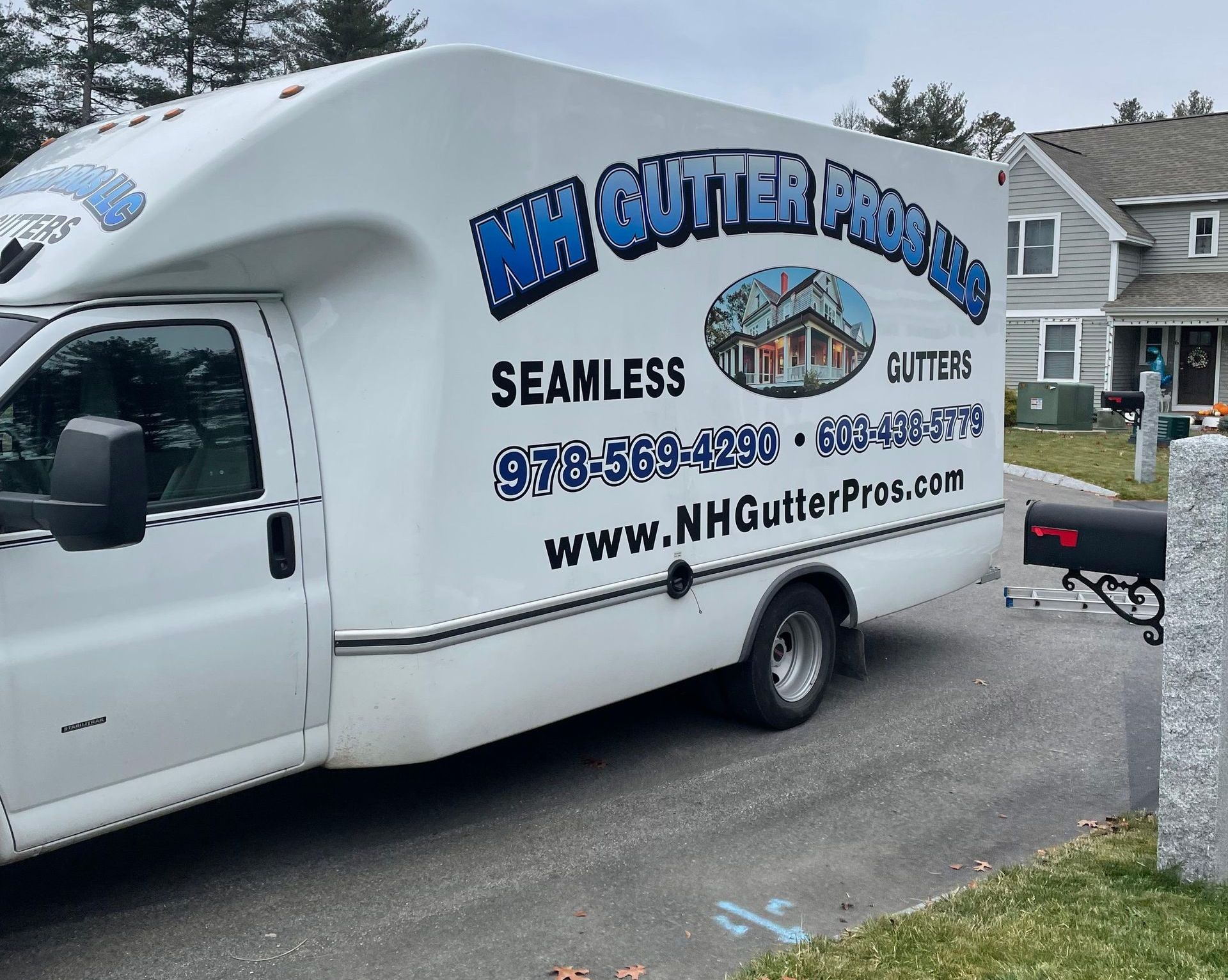 A white gutter cleaning truck is parked in front of a house