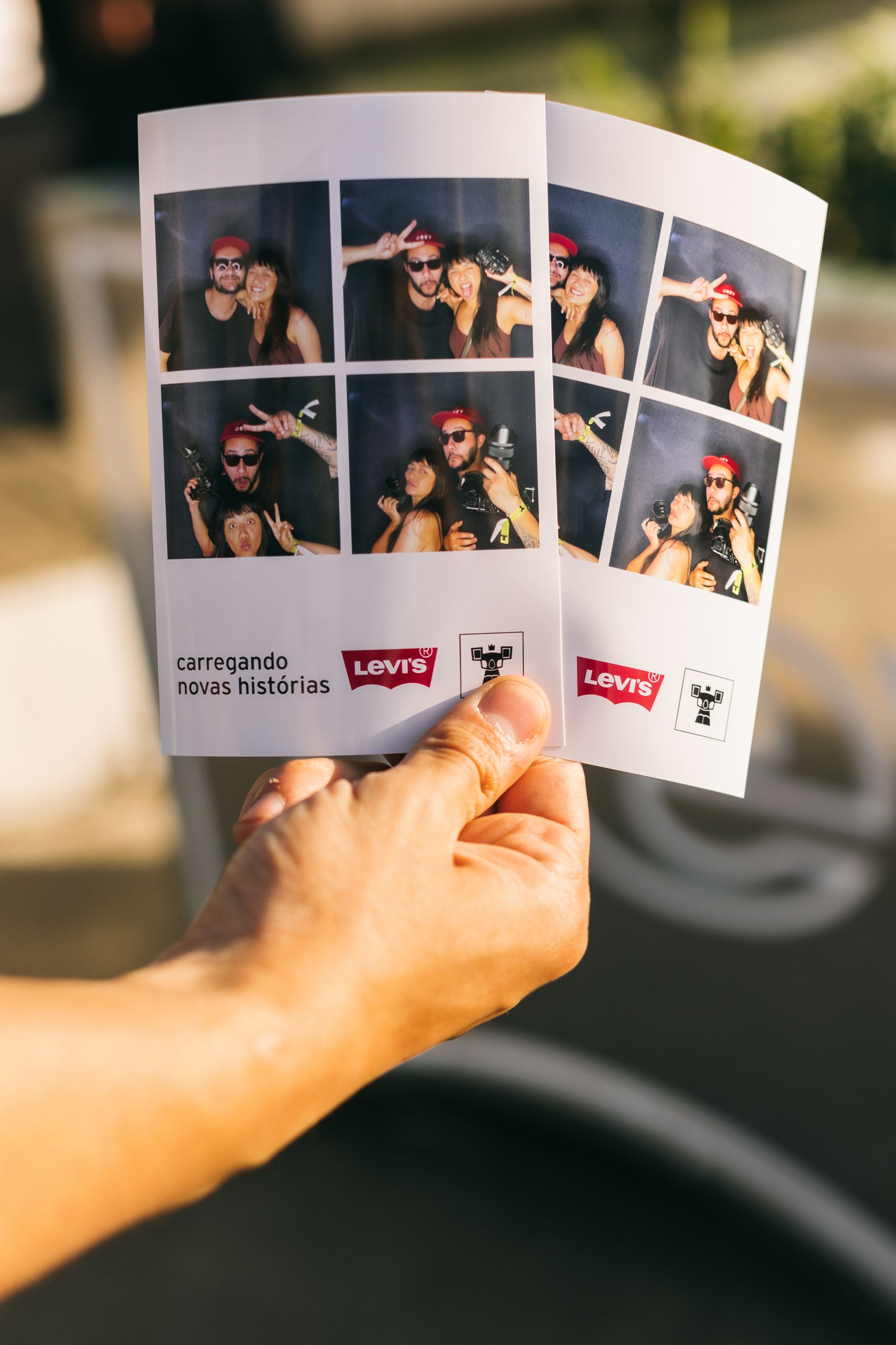 Uma pessoa está segurando um ingresso de cabine fotográfica na mão.