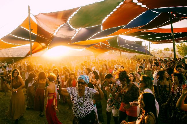 Uma multidão de pessoas dançando sob guarda-chuvas em um festival
