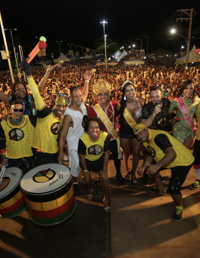 Um grupo de pessoas está posando para uma foto na frente de uma multidão.