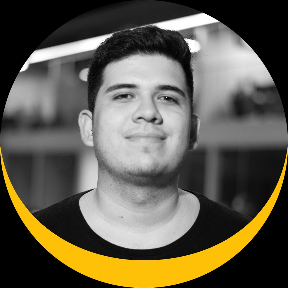 Um homem de camisa preta está sorrindo em uma foto em preto e branco.