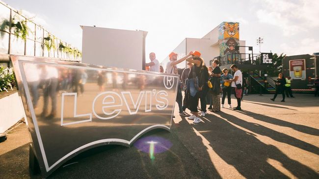 Um grupo de pessoas está em frente a uma placa da Levis.