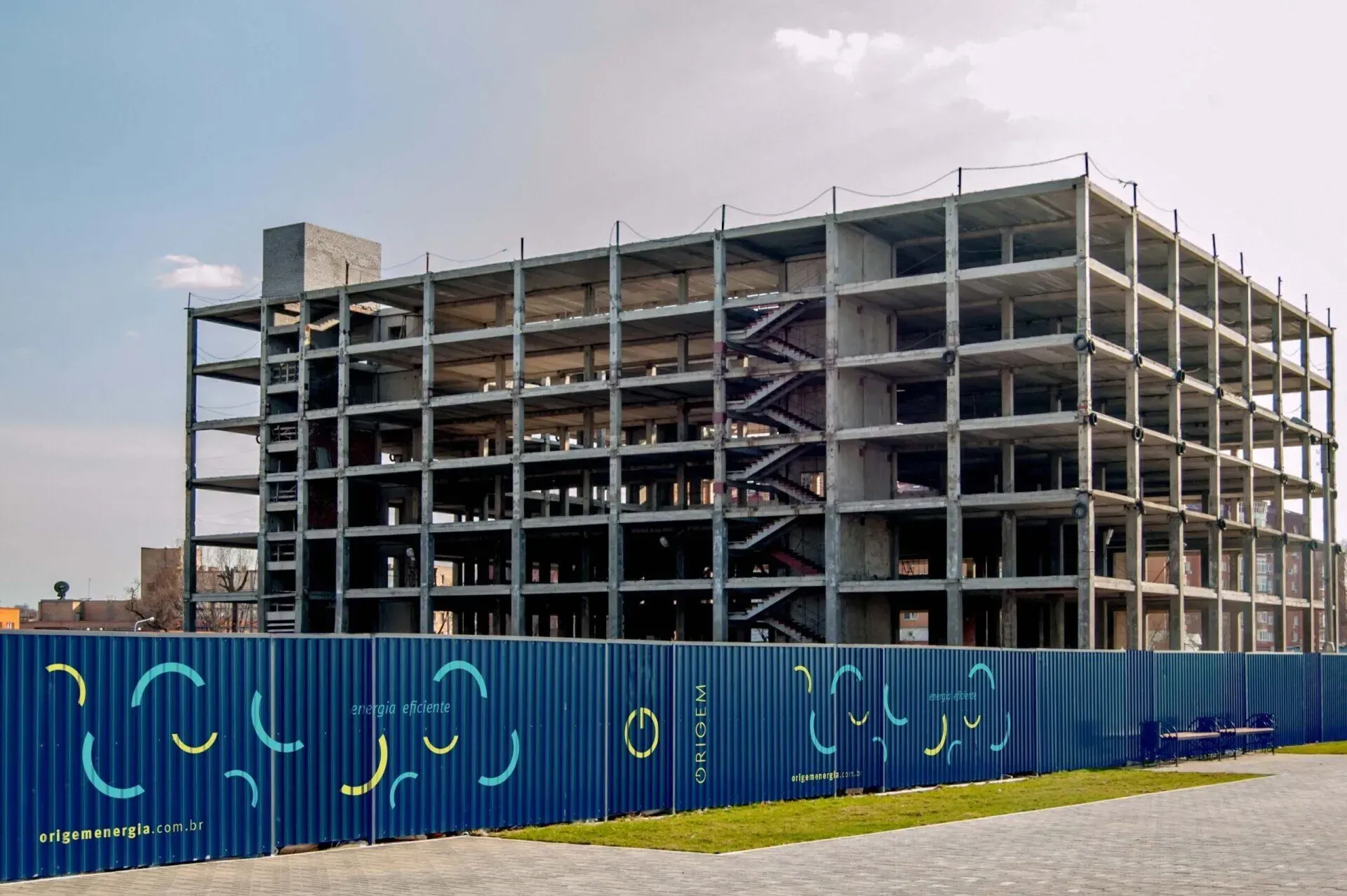 Um grande edifício em construção está atrás de uma cerca azul.