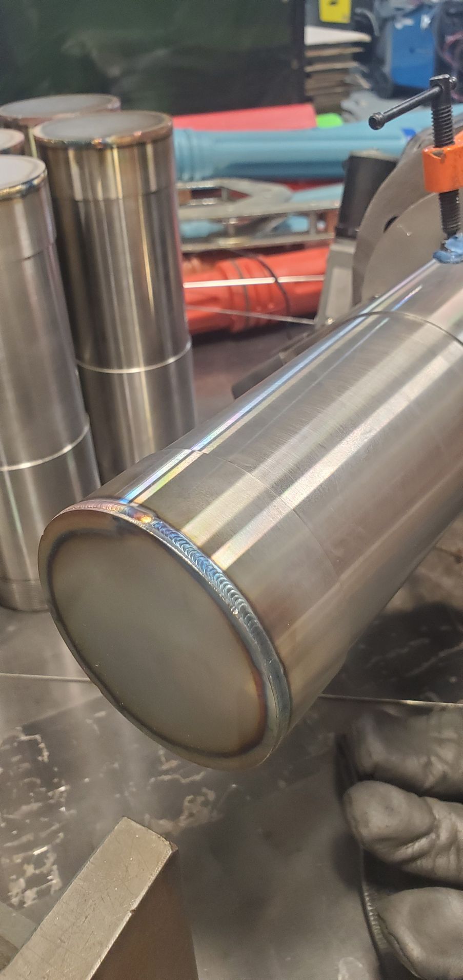 A person is welding a stainless steel pipe on a table.