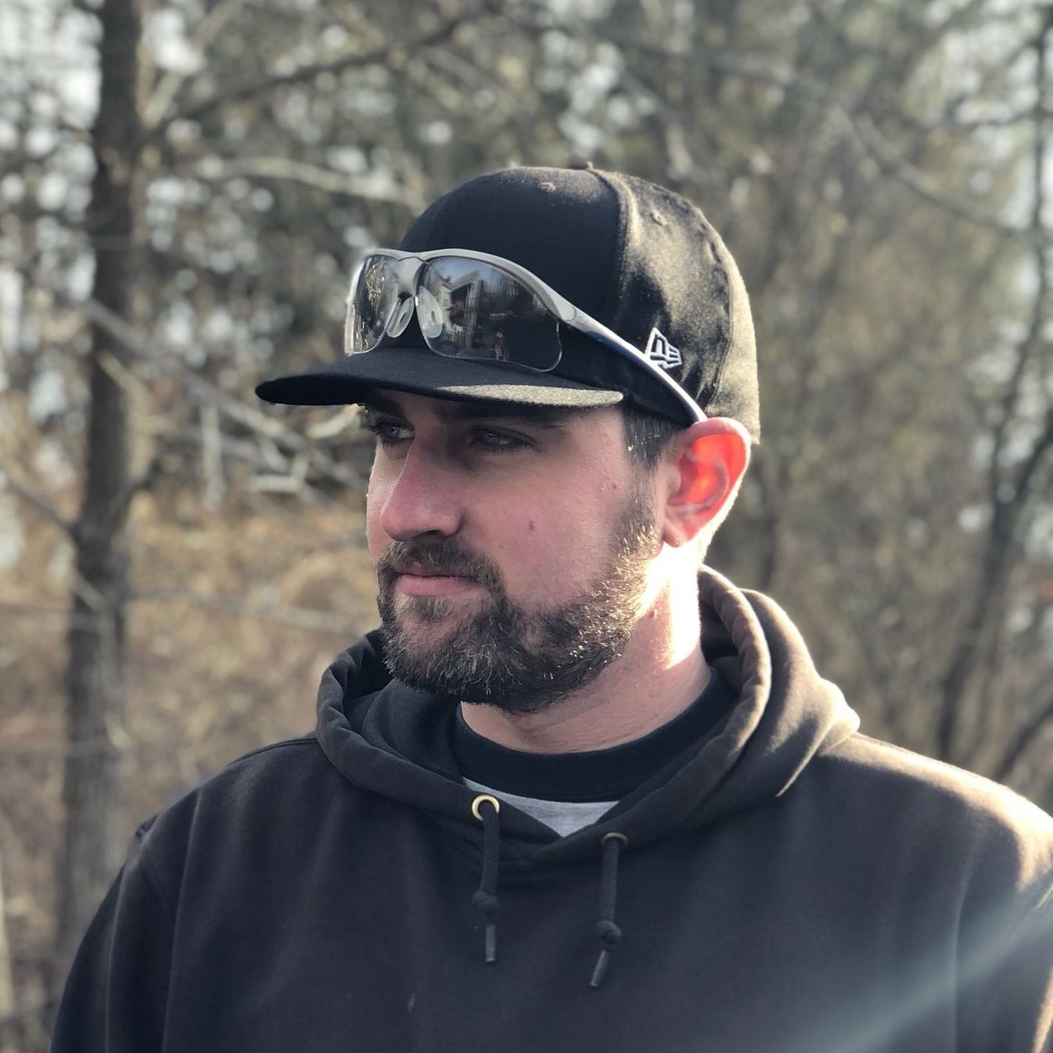 A man with a beard wearing a baseball cap and sunglasses