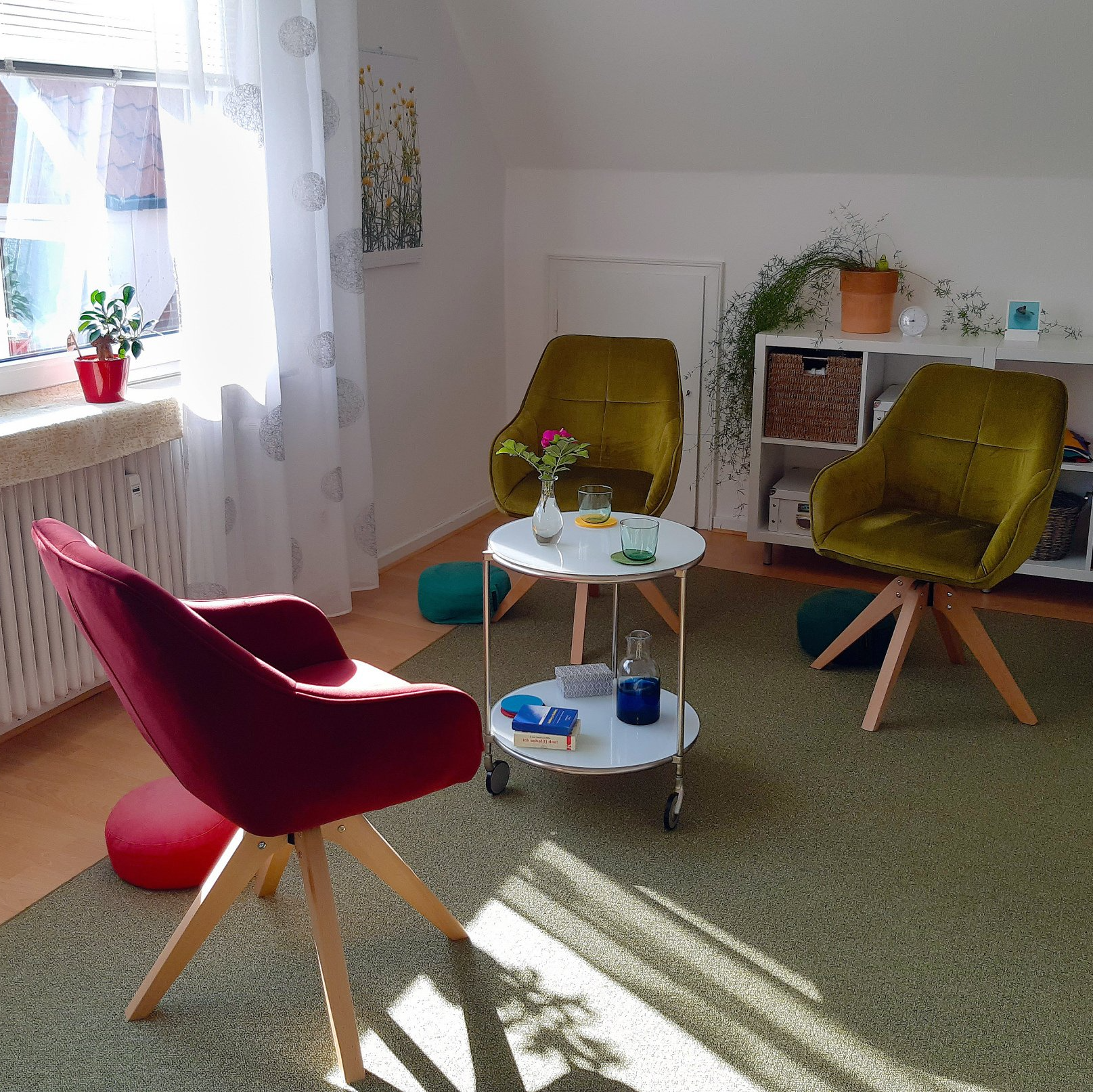 Helles Zimmer mit farbenfrohen Sesseln, einem kleinen runden Tisch und Sonnenlicht, das durch ein Fenster fällt