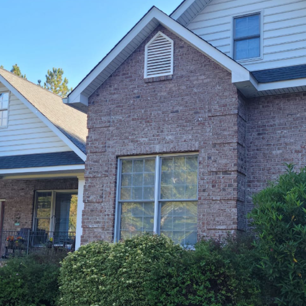 a brick house with a white siding and a large window