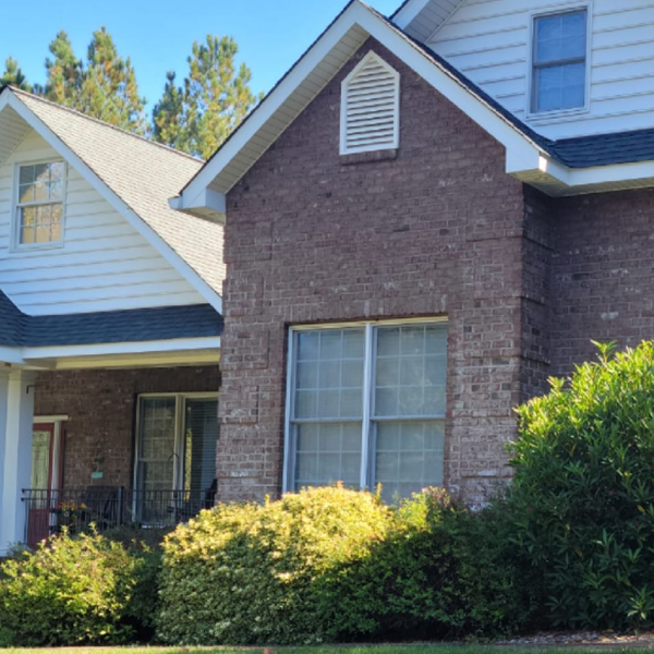 a brick house with a white siding and a black roof
