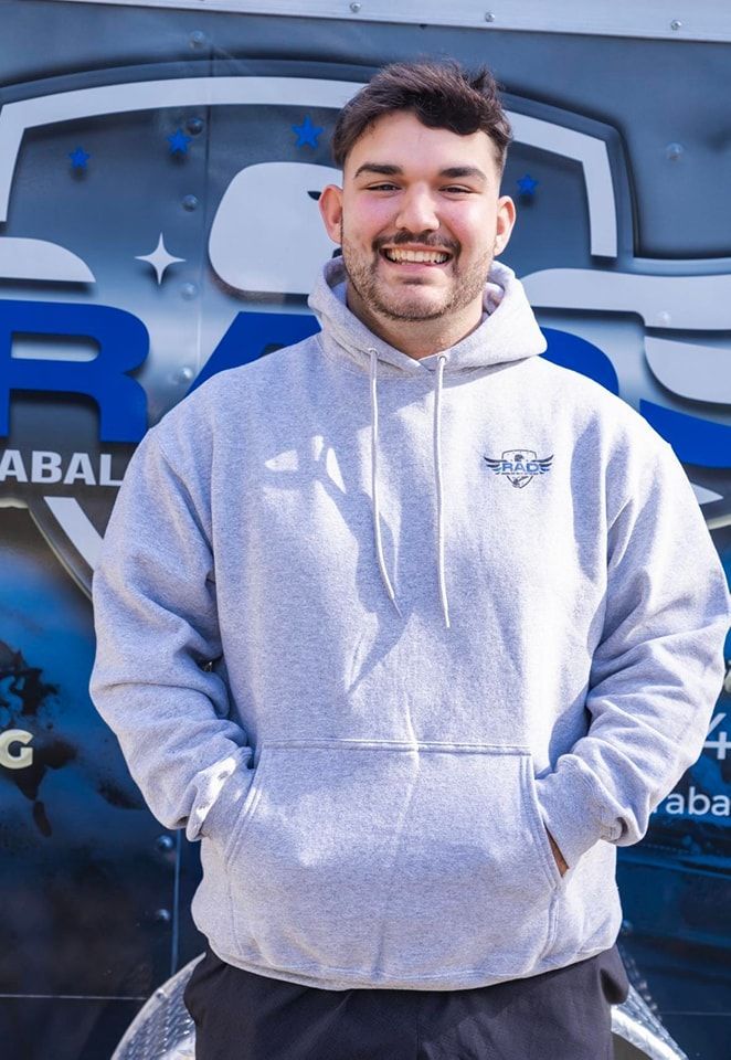 A man wearing a grey hoodie is standing in front of a truck.
