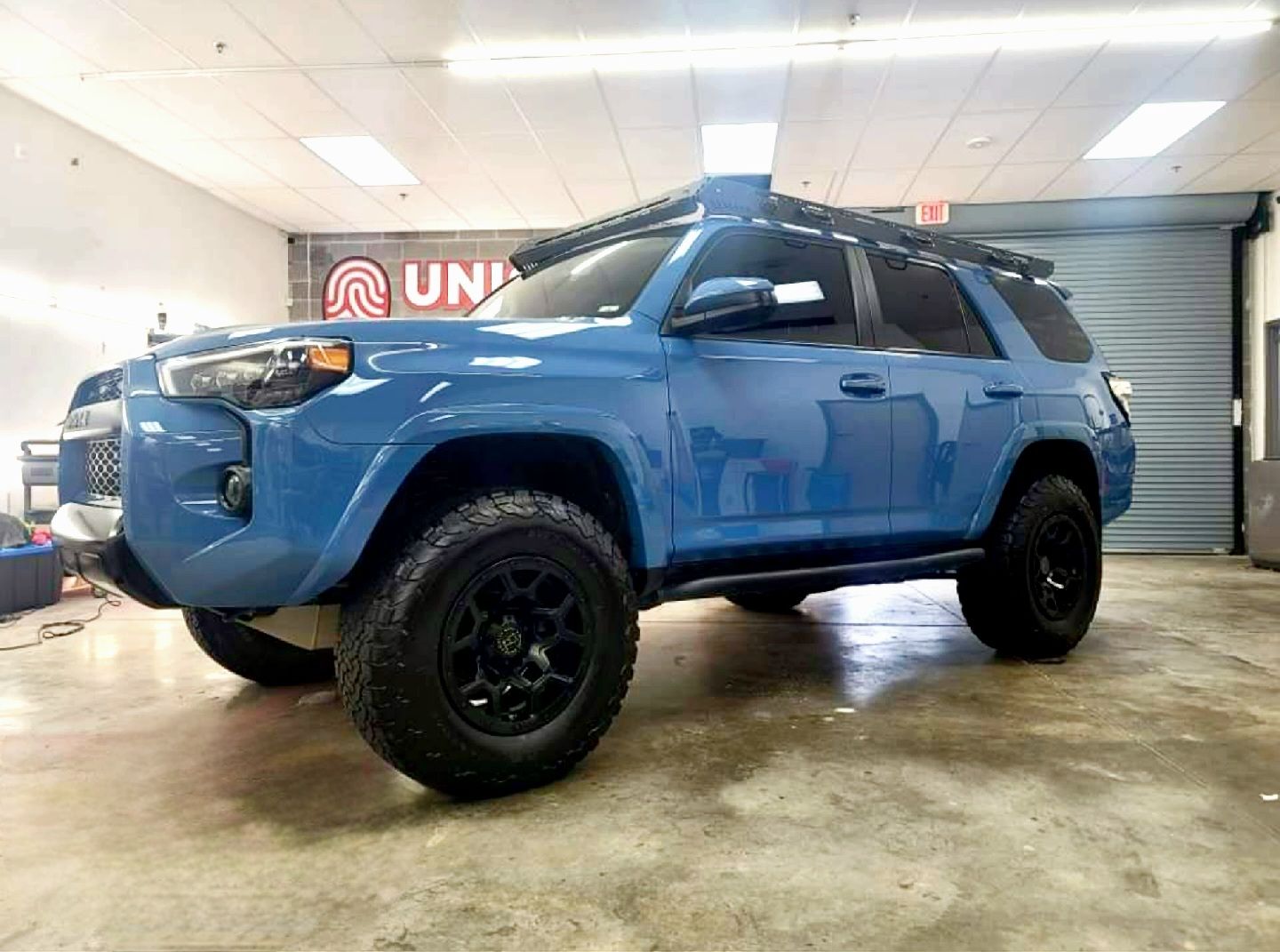 A blue toyota 4runner is parked in a garage.