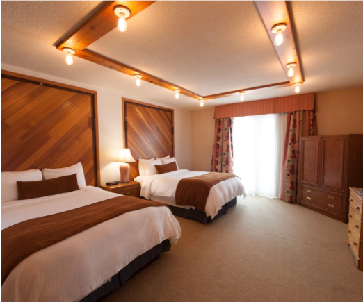 A hotel room with two beds and a television