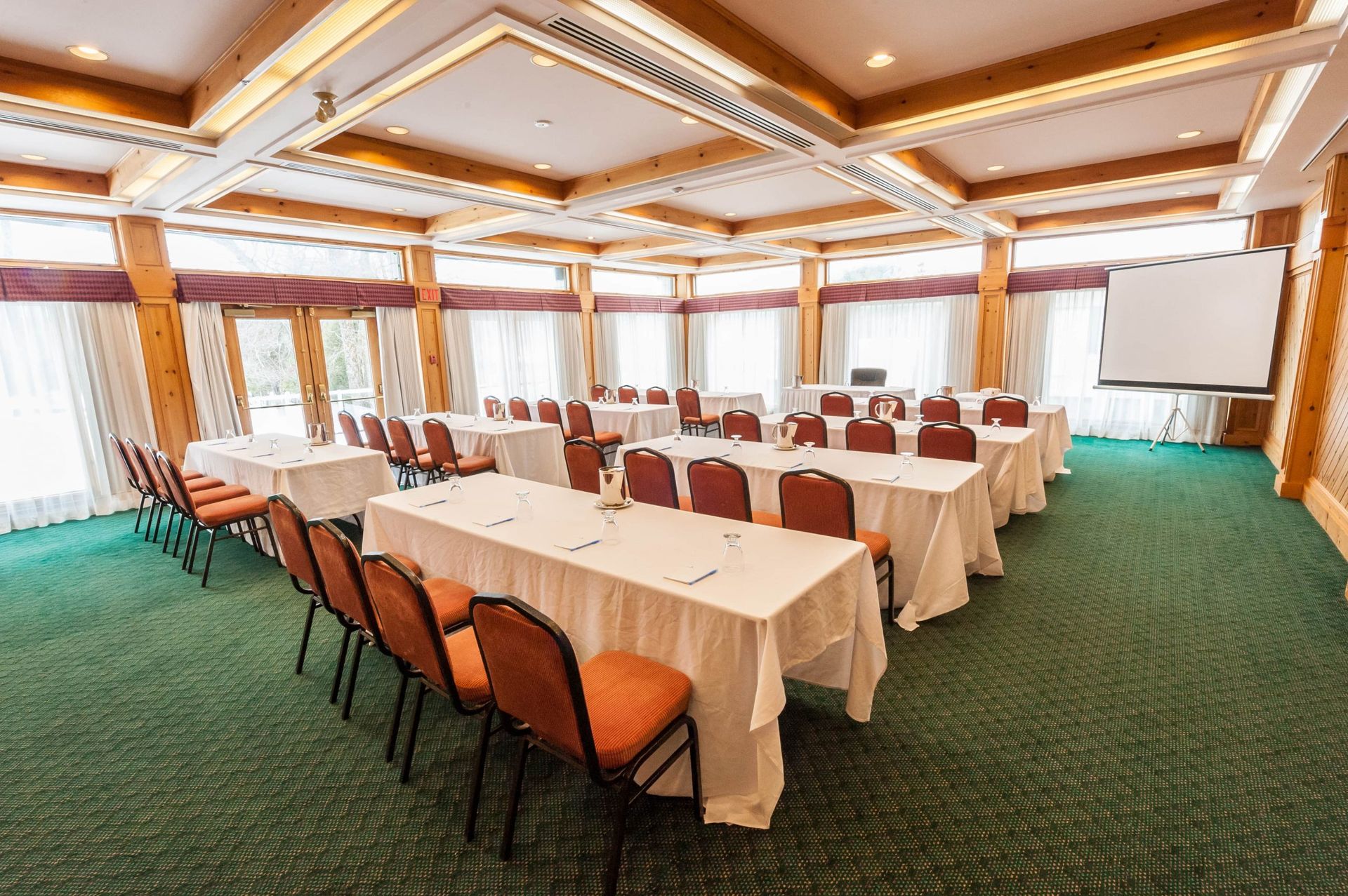 A large conference room with tables and chairs and a projector screen.