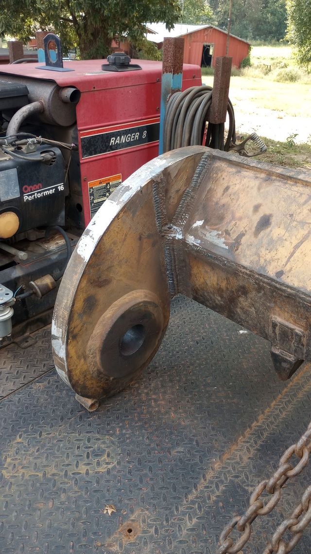 Rusty excavator bucket attached to a red tractor in an outdoor yard