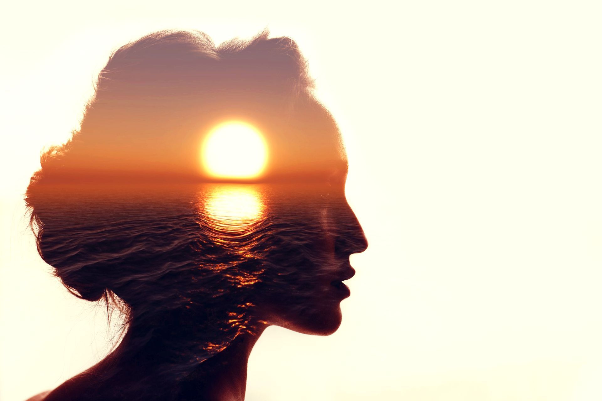 Uma dupla exposição da cabeça de uma mulher com o sol refletido no oceano.
