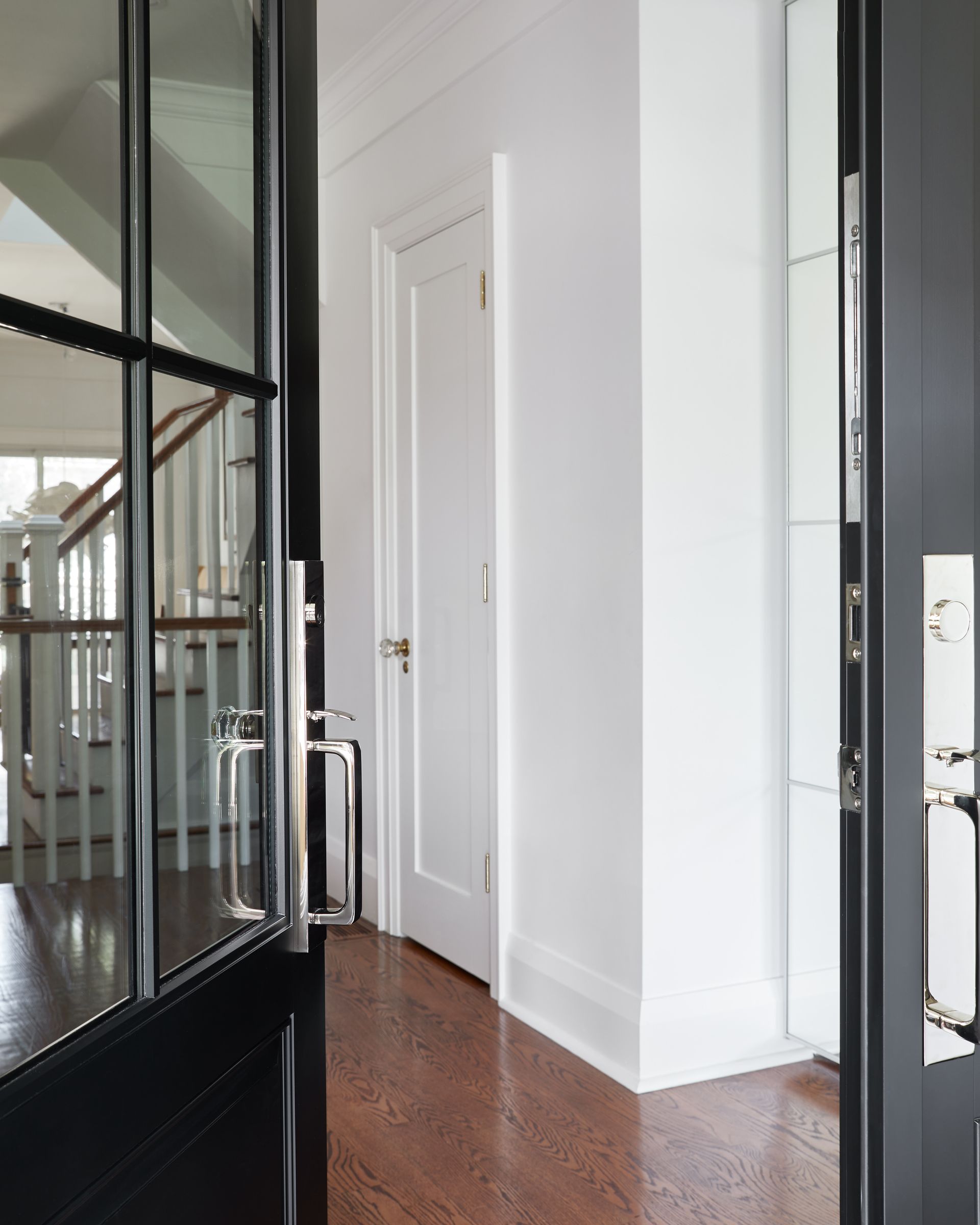 A hallway with a black door and white walls