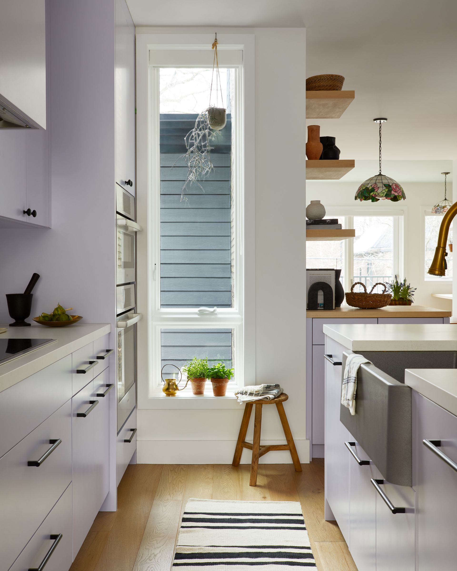 A kitchen with white cabinets and a striped rug on the floor
