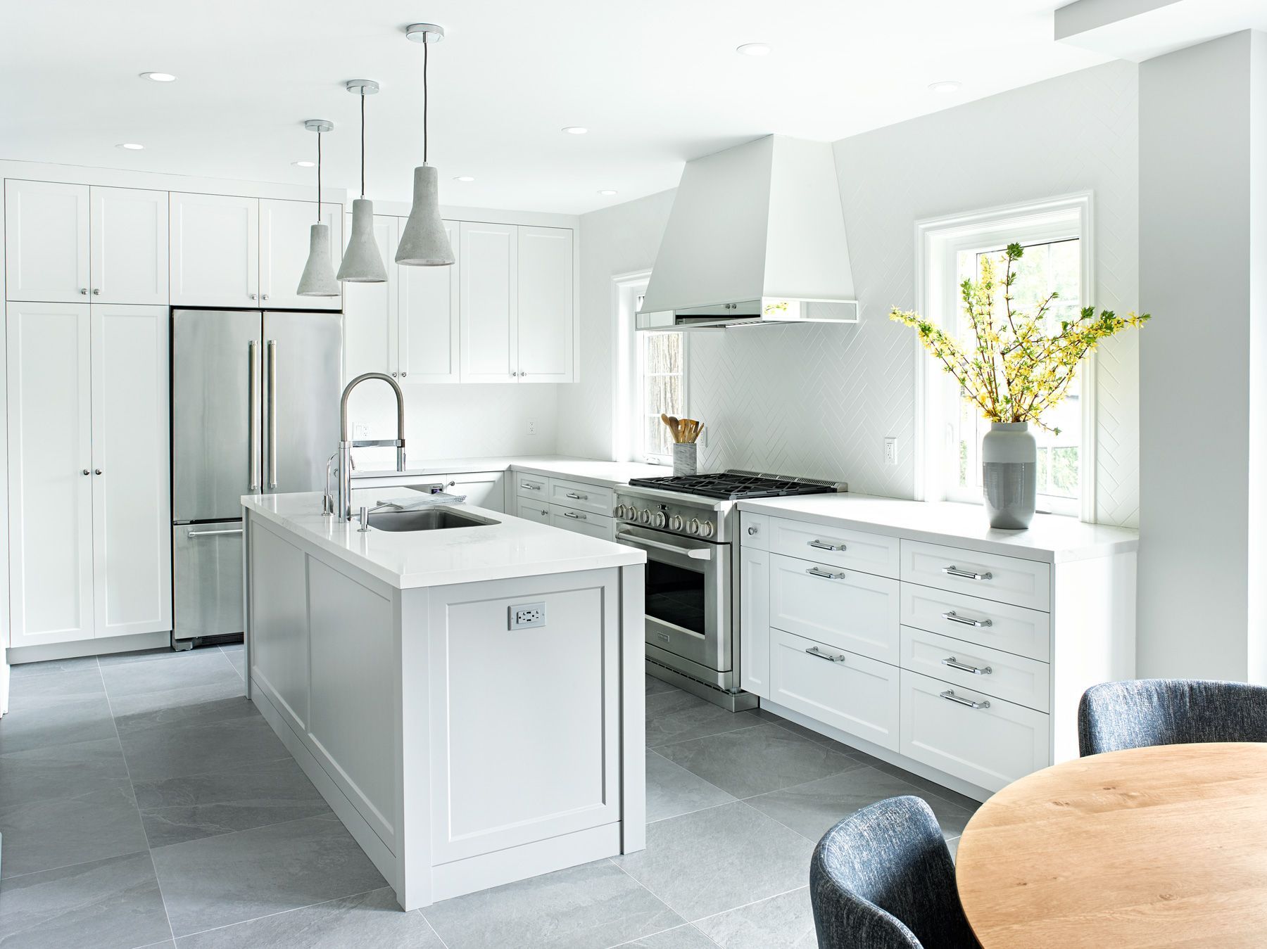 A kitchen with white cabinets , stainless steel appliances , and a large island.