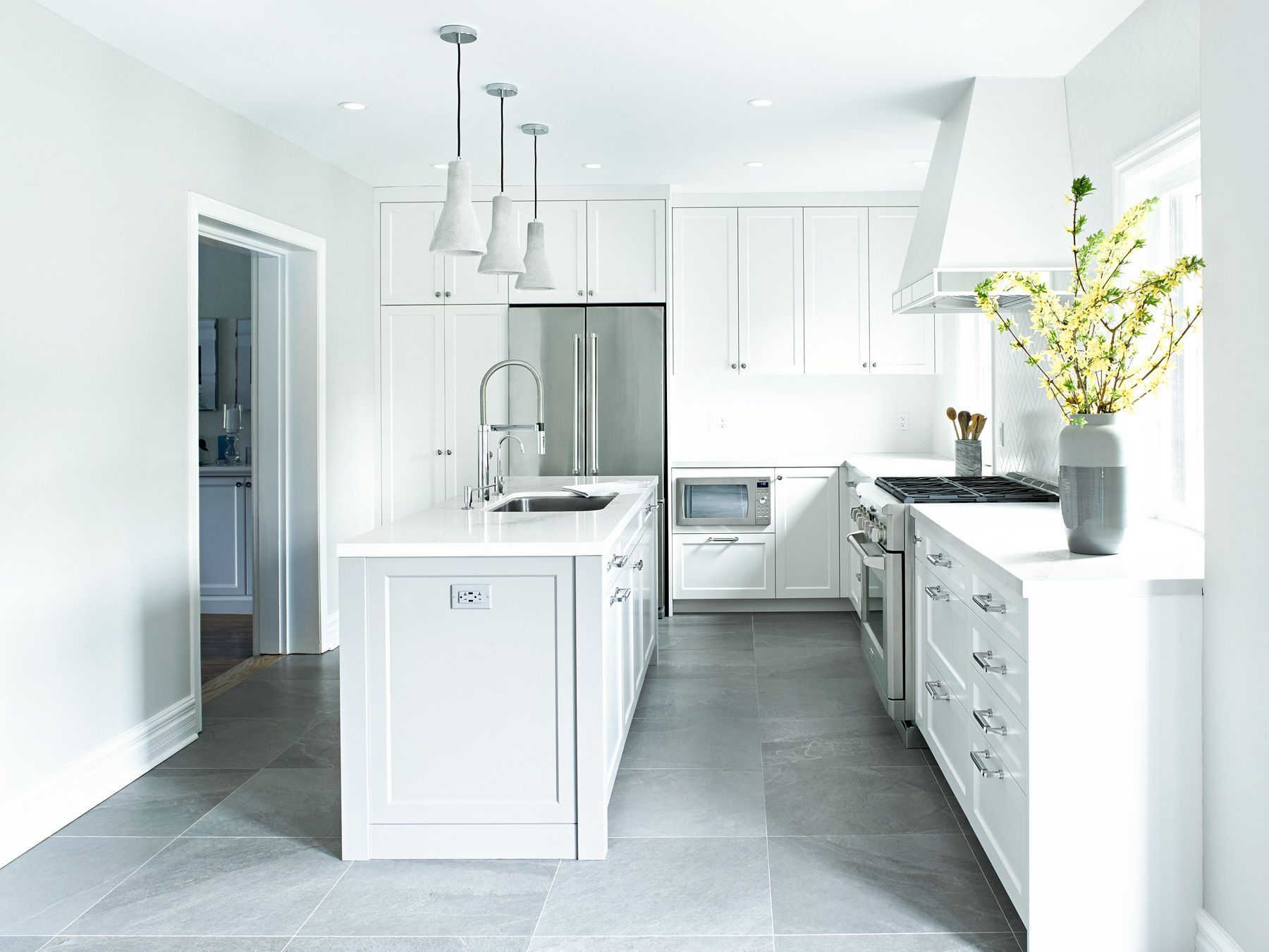 A kitchen with white cabinets , stainless steel appliances , and a large island.