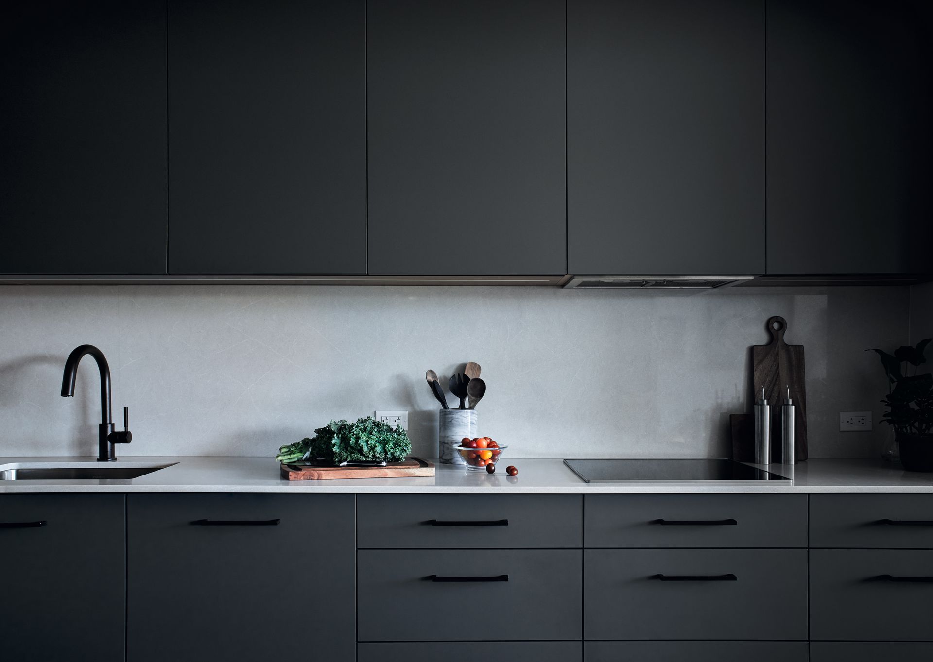 A kitchen with black cabinets , a sink , and a stove top oven.