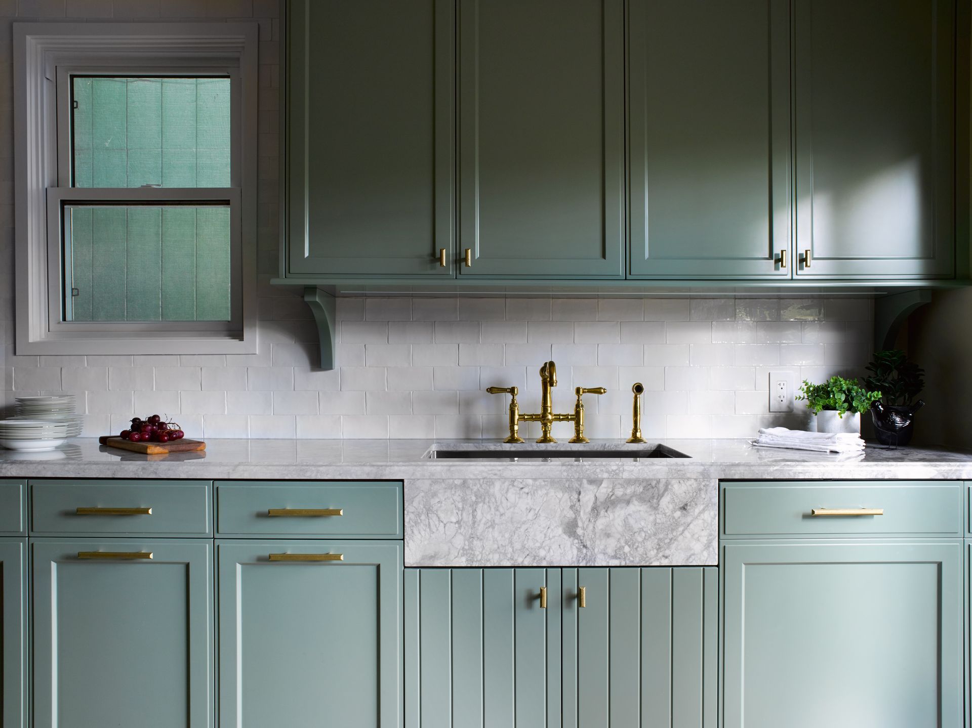 A kitchen with green cabinets and a white sink.