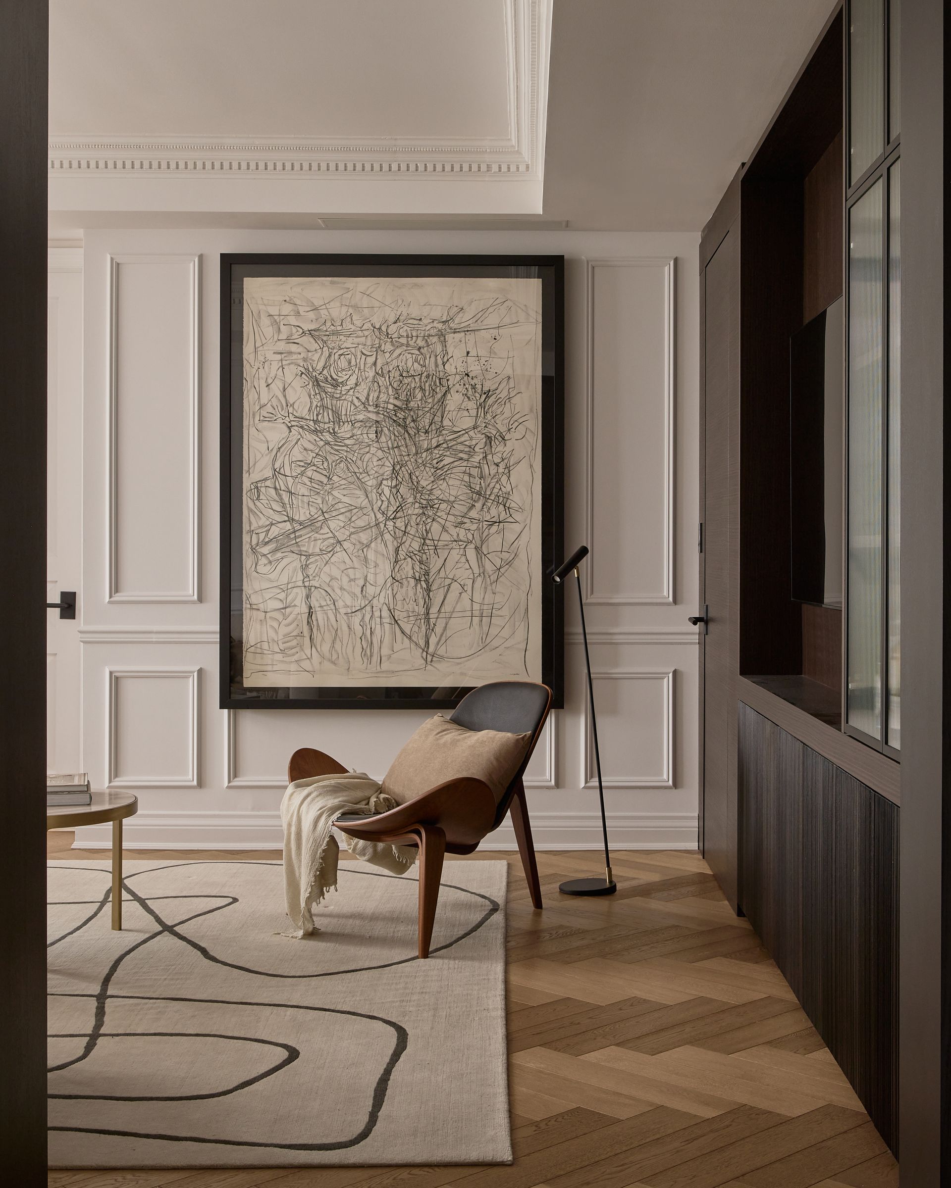 A living room with a chair and a large painting on the wall.