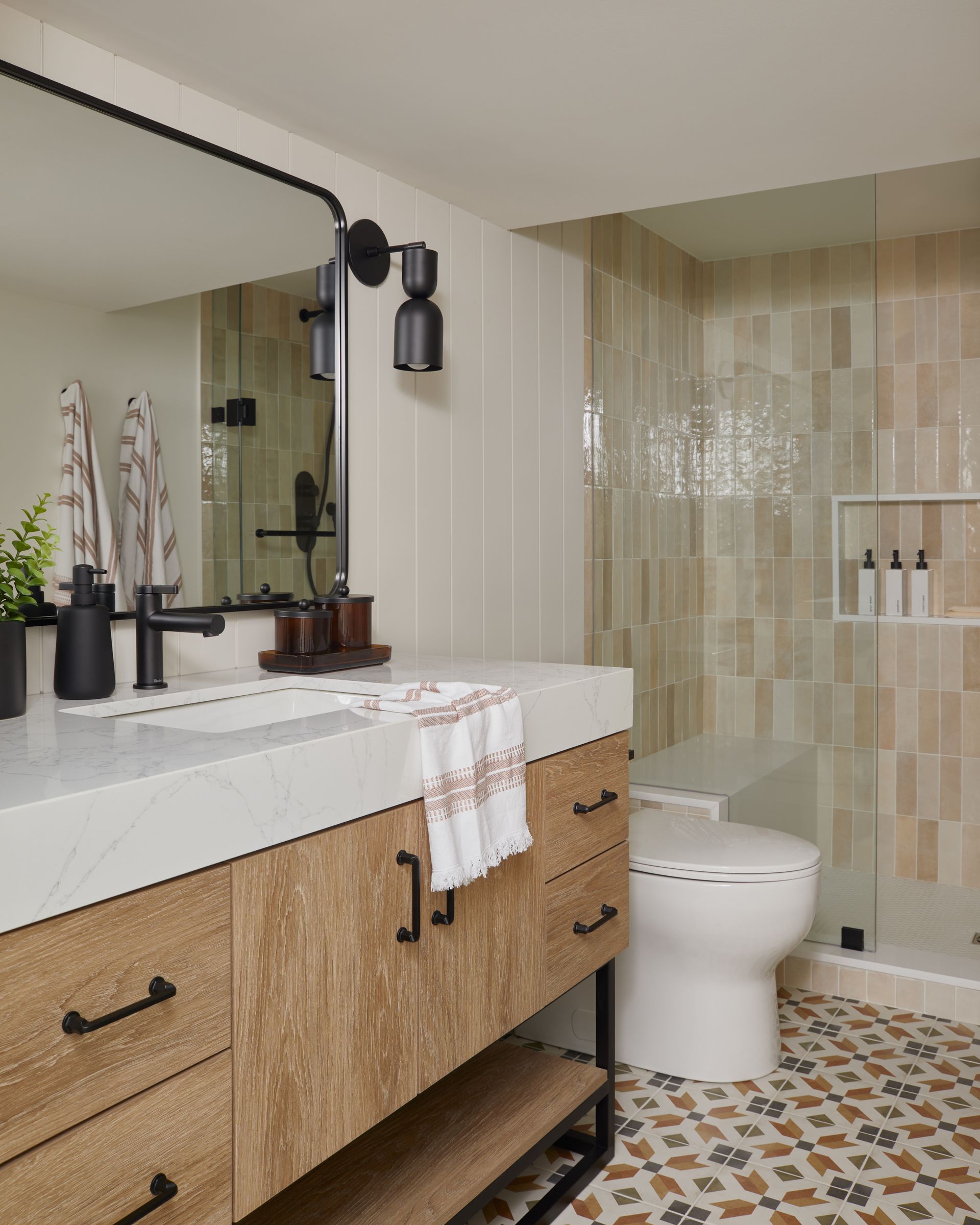 A bathroom with a sink , toilet , shower and mirror.