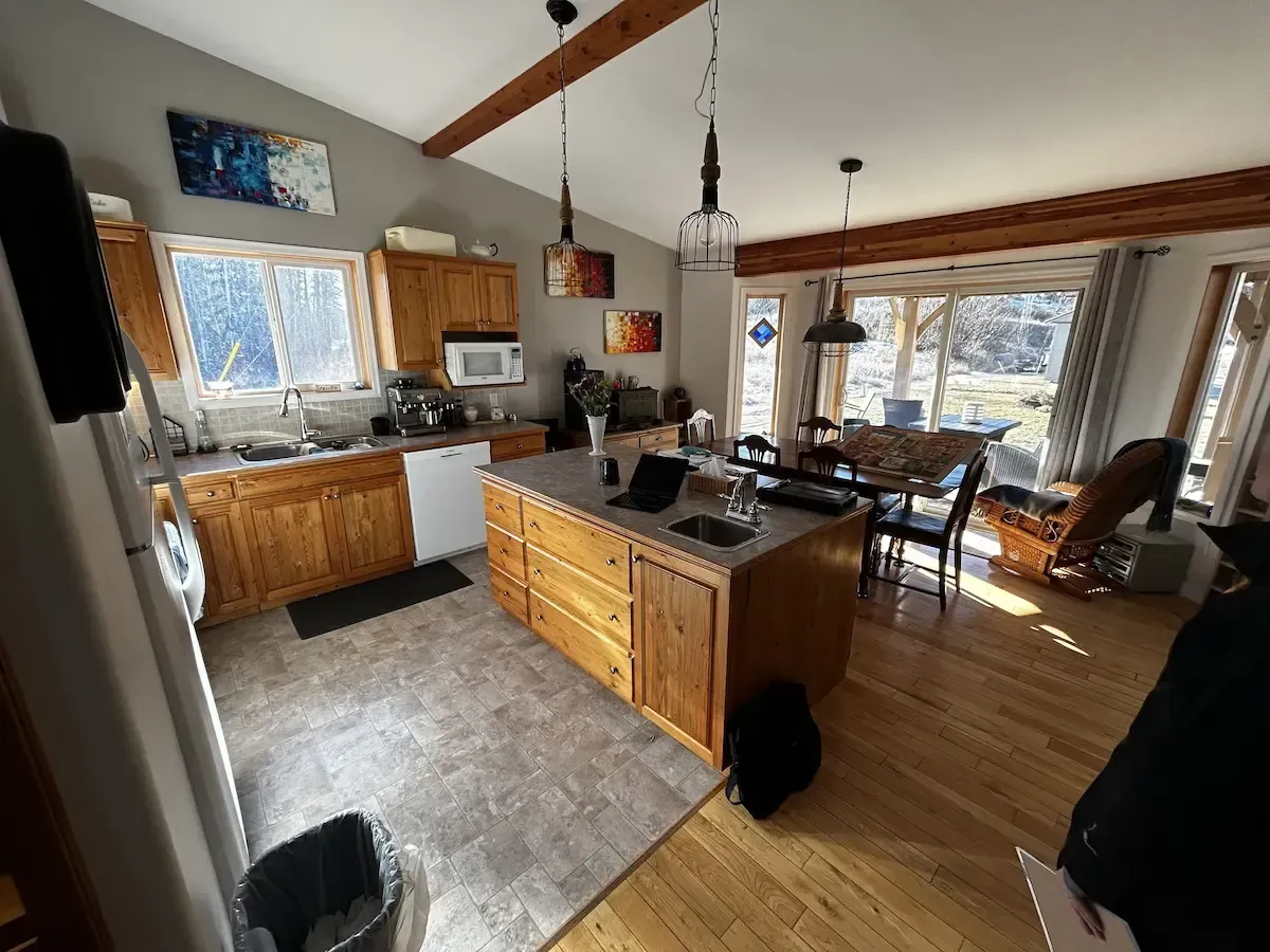 Bright open kitchen and dining area with wood cabinets, island, large windows, and hardwood floors