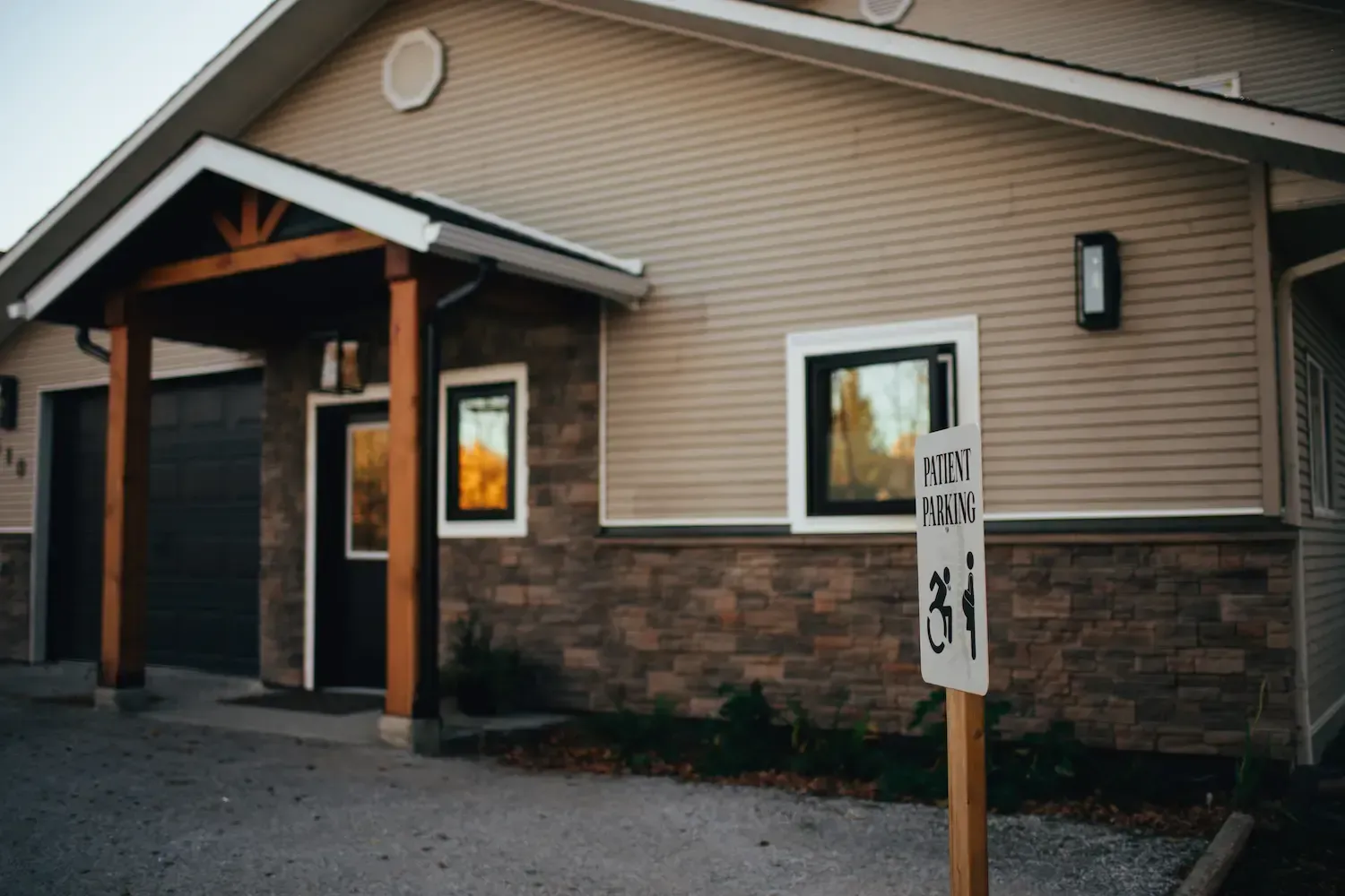 Building entrance with beige siding, stone base, and a posted speed limit sign in front