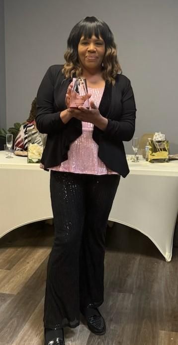 Jillian Bullock holding a crystal award, standing by a decorated table at an award event