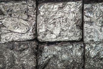 Primo piano di tre blocchi metallici grigi e rugosi, con una superficie ruvida e strutturata.