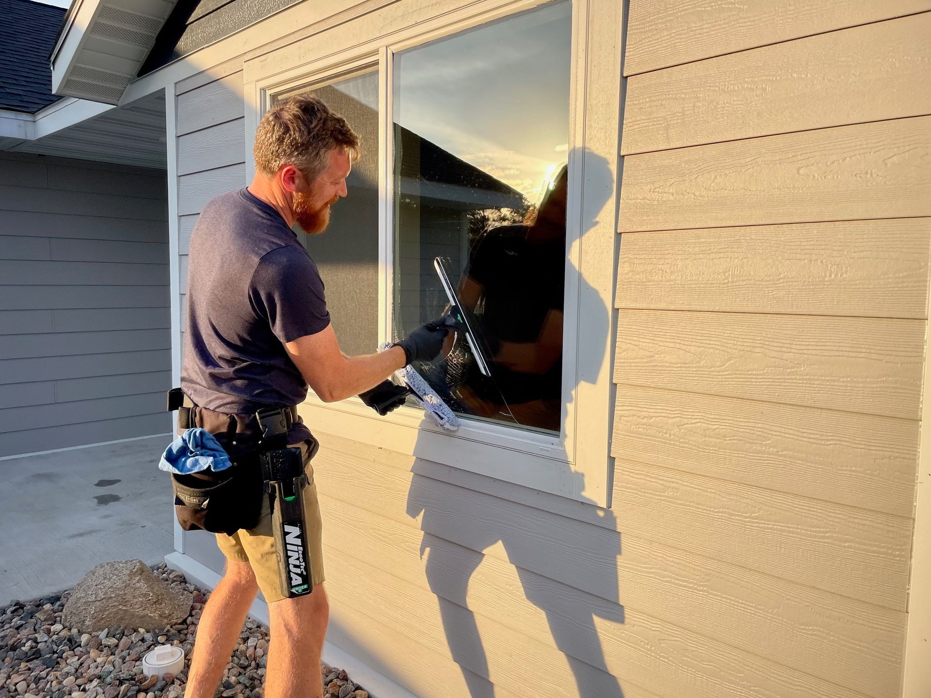A man is cleaning a window on the side of a house.