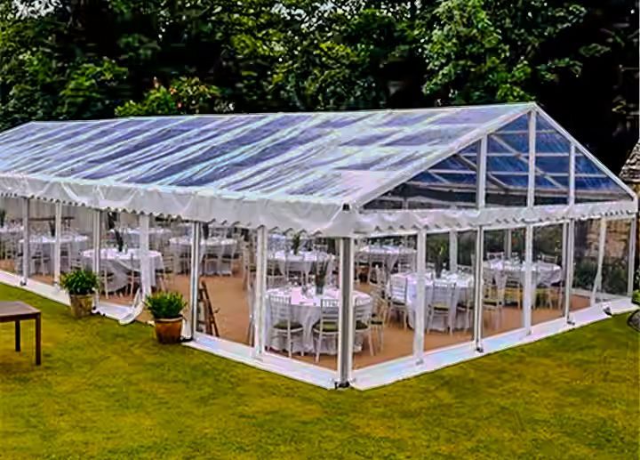 A large clear tent with tables and chairs underneath it.