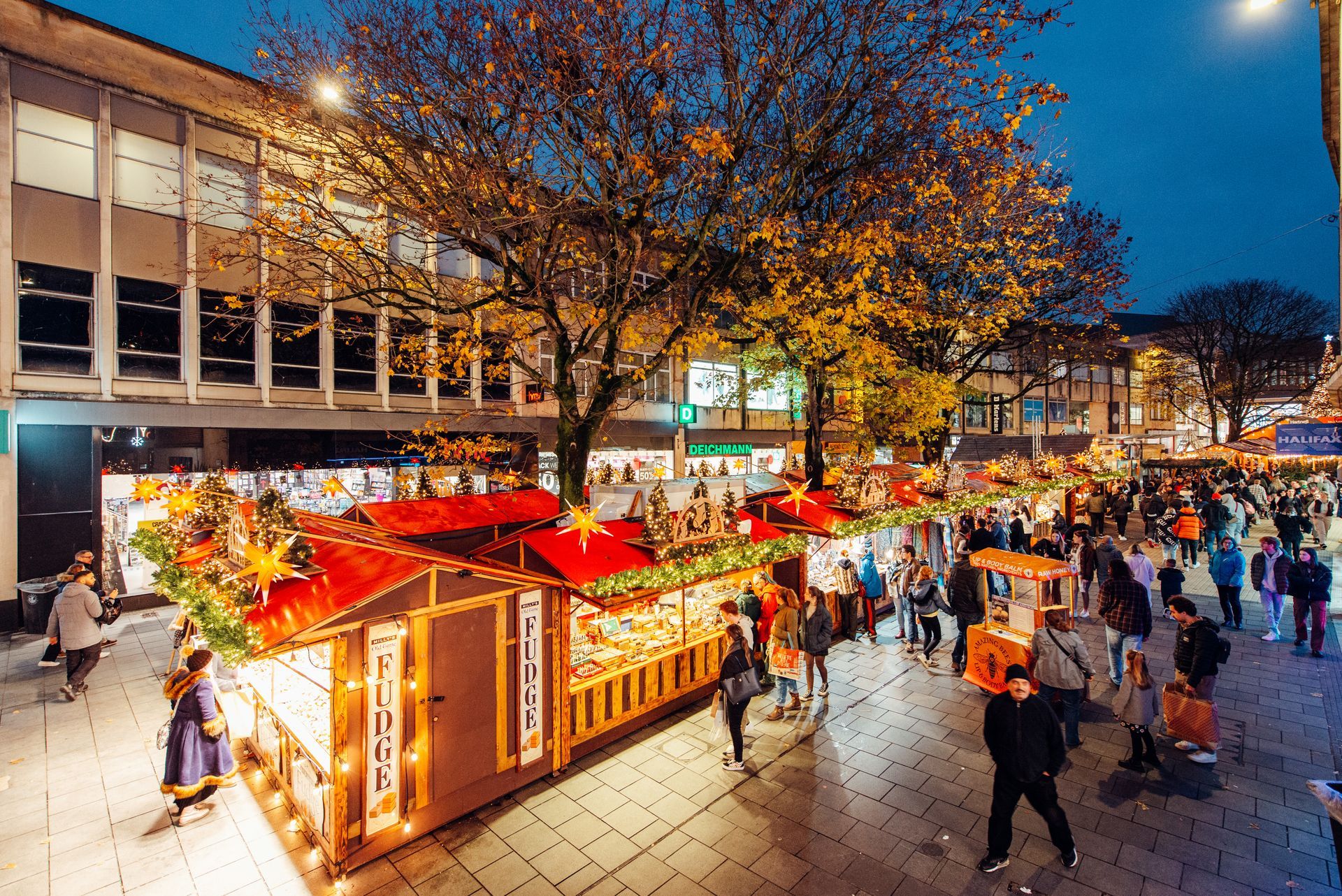 A crowd of people are walking around a christmas market
