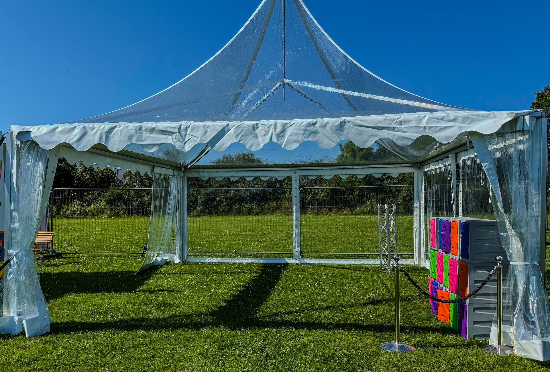 A clear tent is in the middle of a grassy field