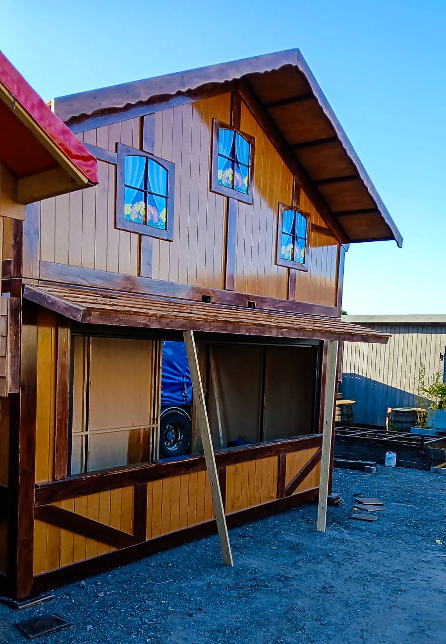 A wooden house with a red roof and a ladder in front of it