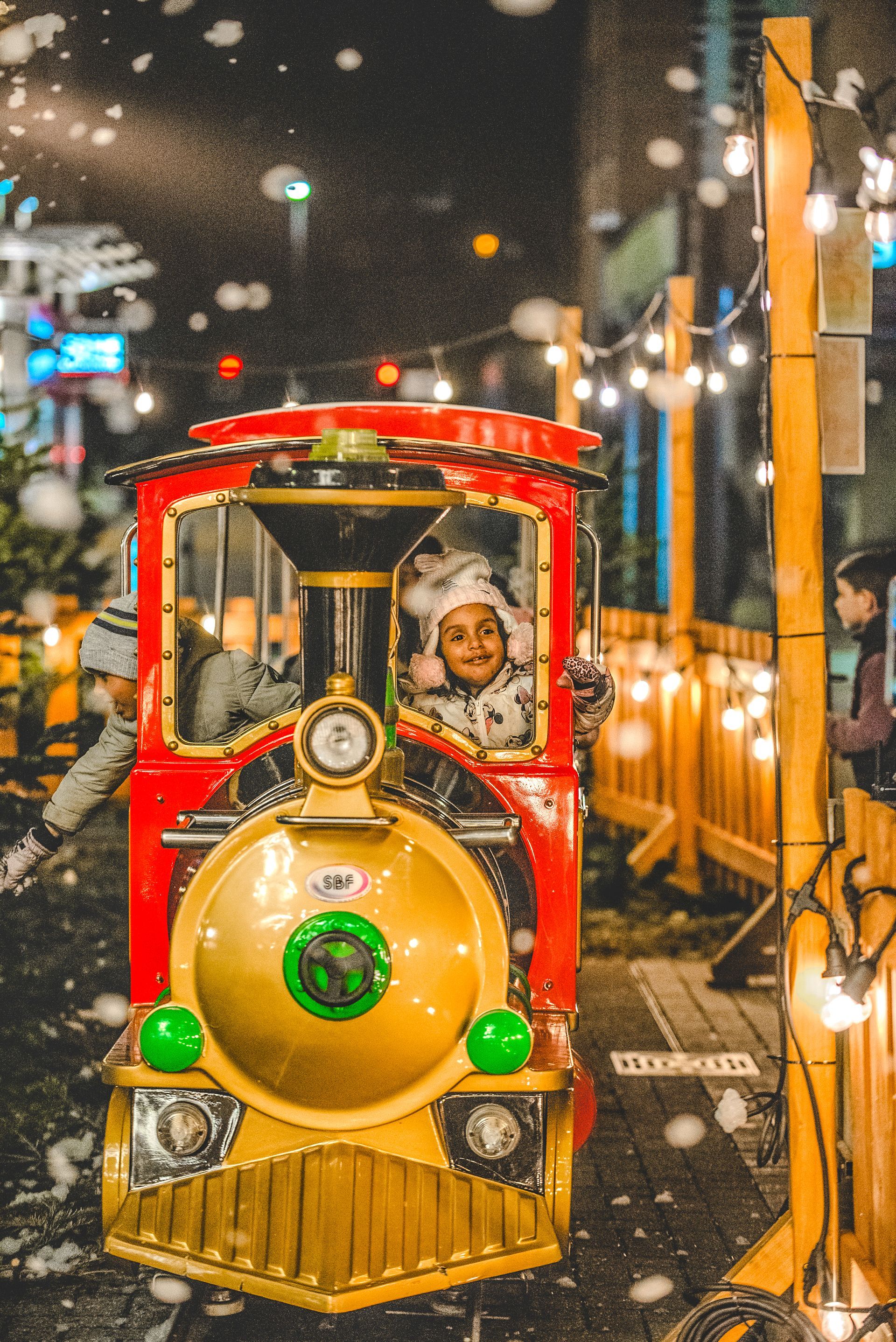 A little girl in a santa hat is riding a train