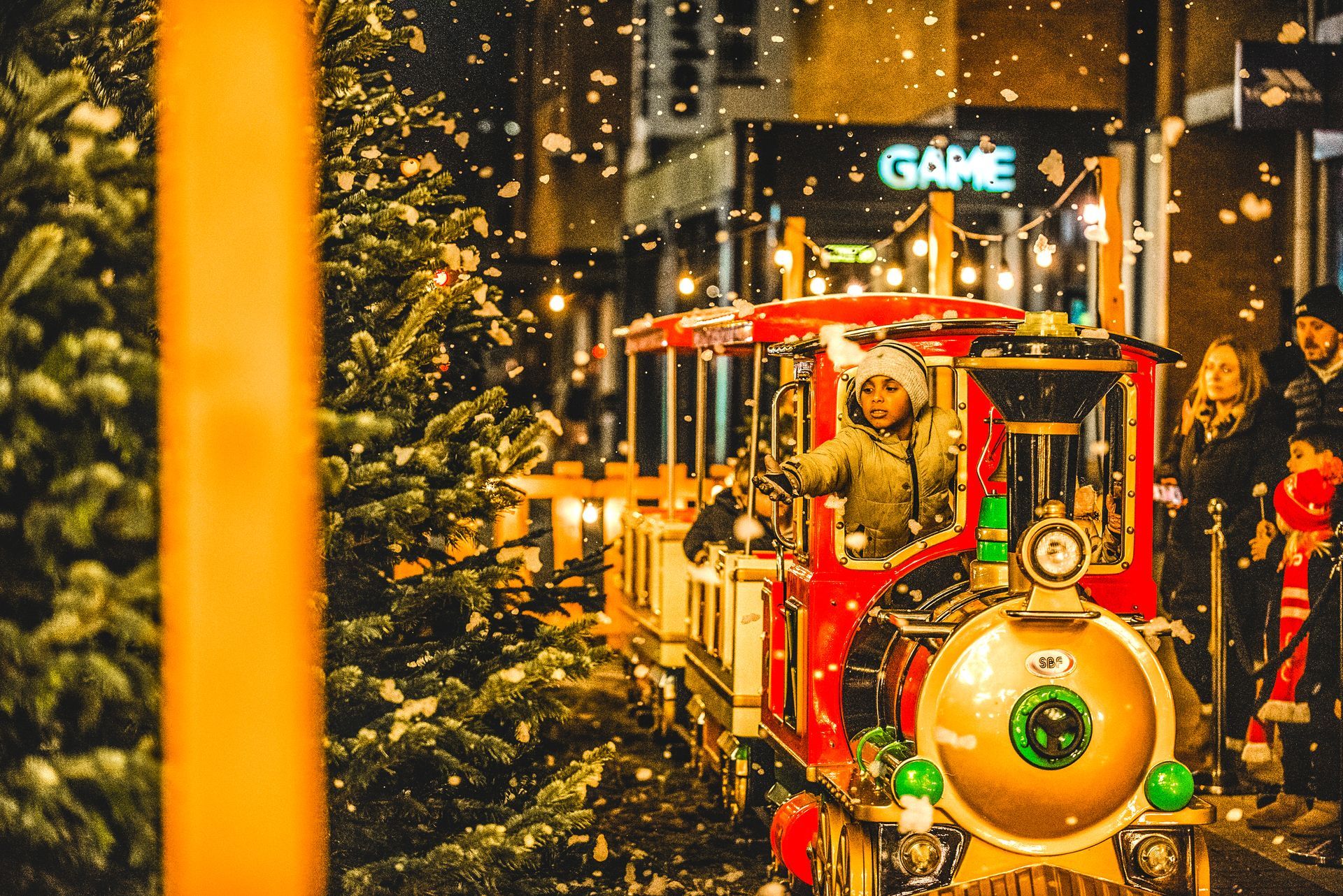 A train is going down a street with a game sign in the background