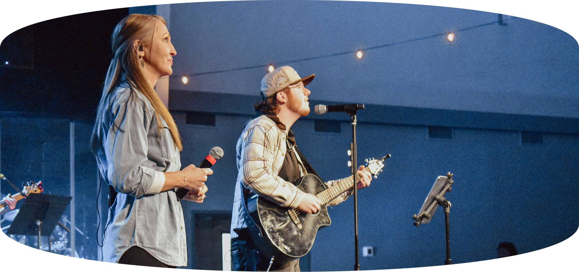 Two musicians performing onstage with guitars under blue lighting