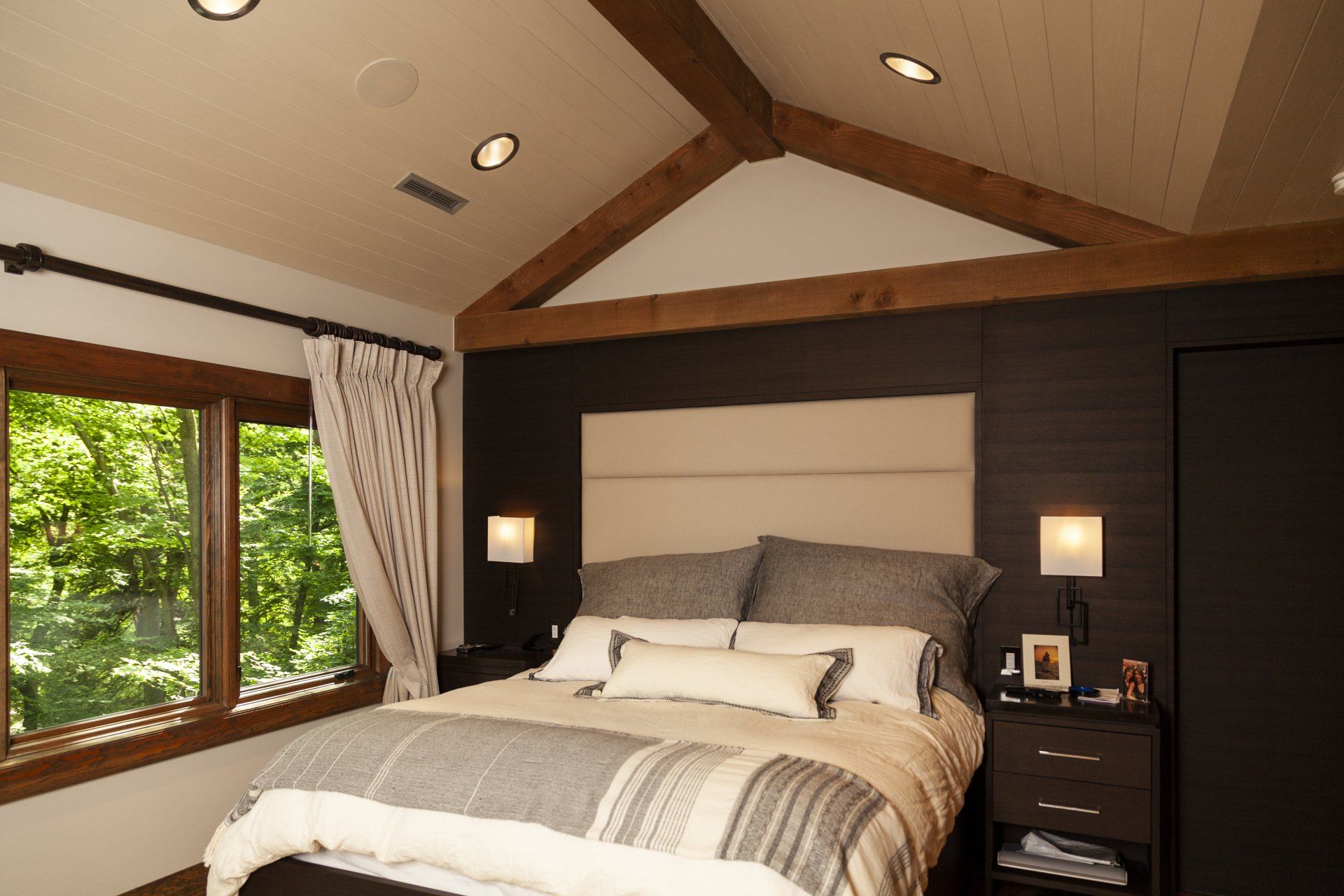A bedroom with a vaulted timber frame ceiling and a bed