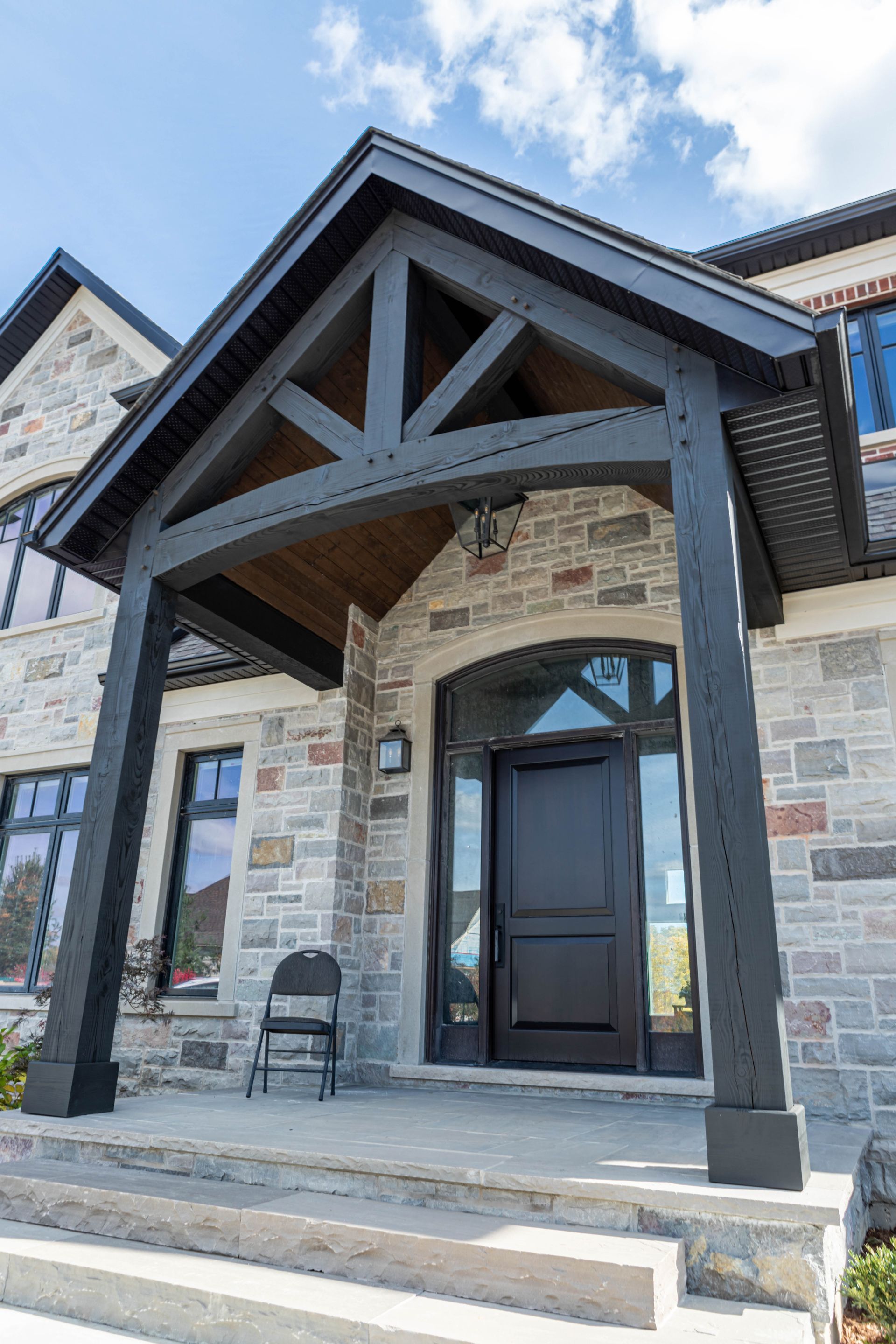 A large stone house with a black door and a timber frame porch.