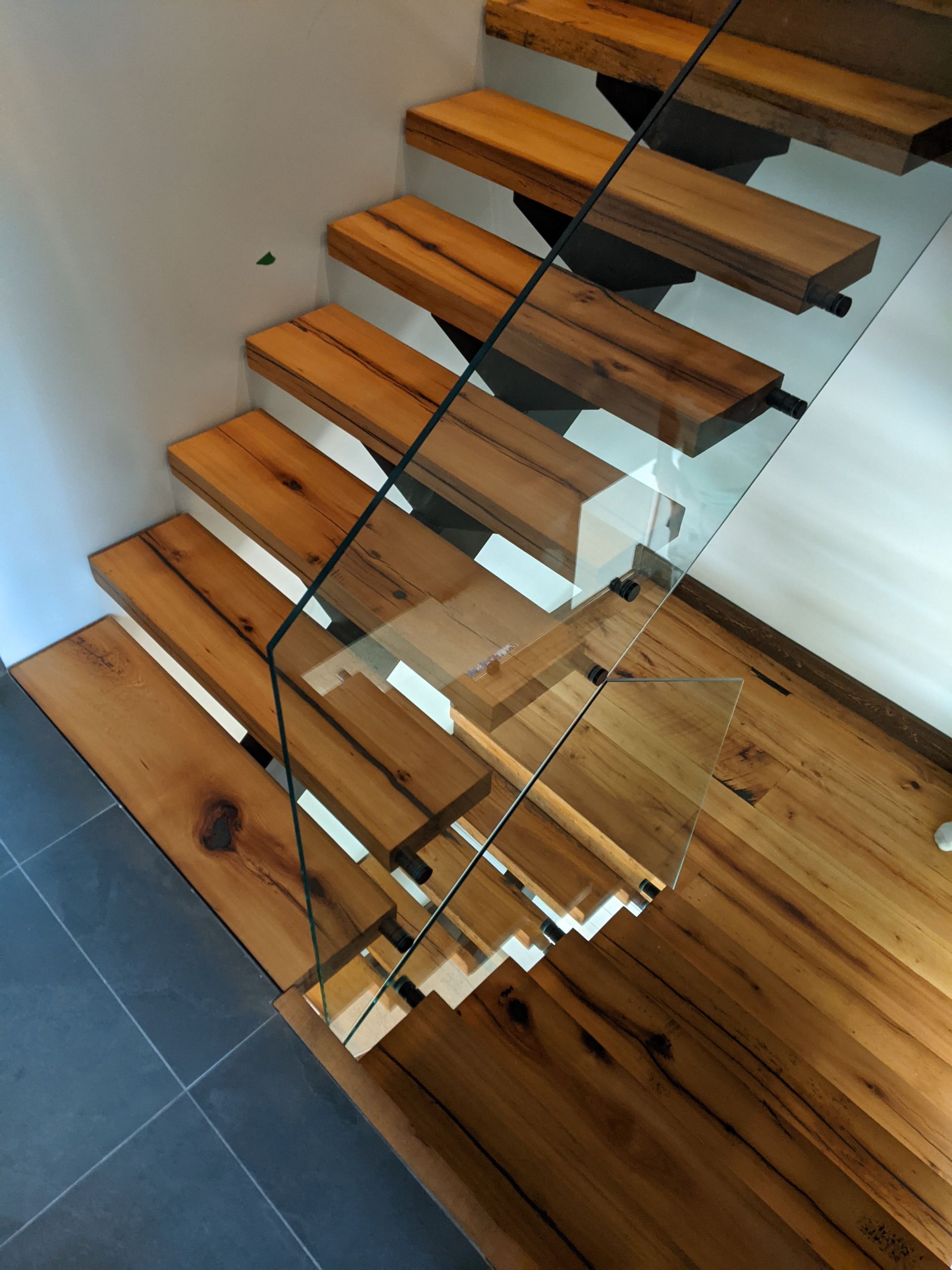 Wooden floating staircase with glass railing.